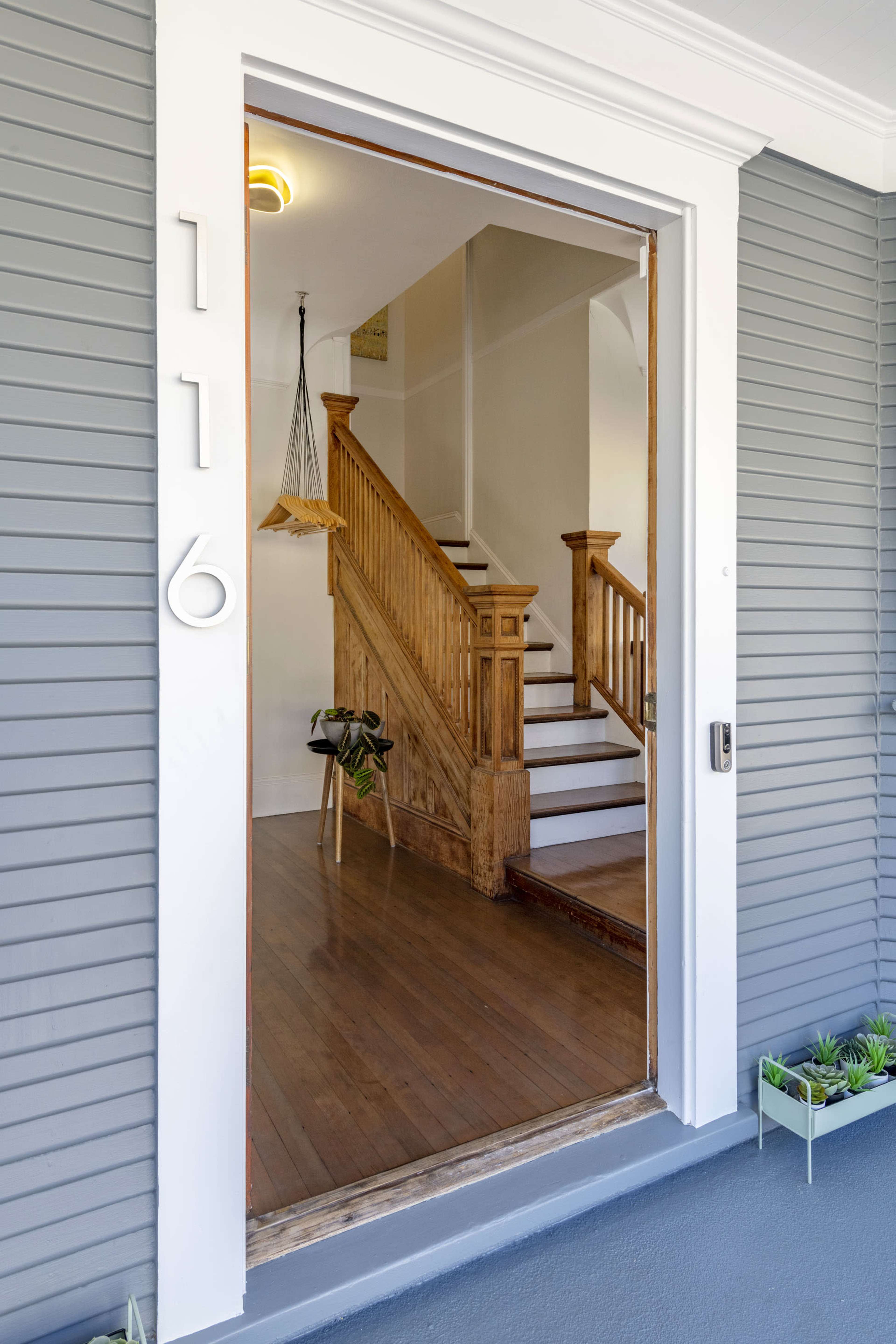 An entrance to a house featuring a wooden staircase and a decorative wall hanging.