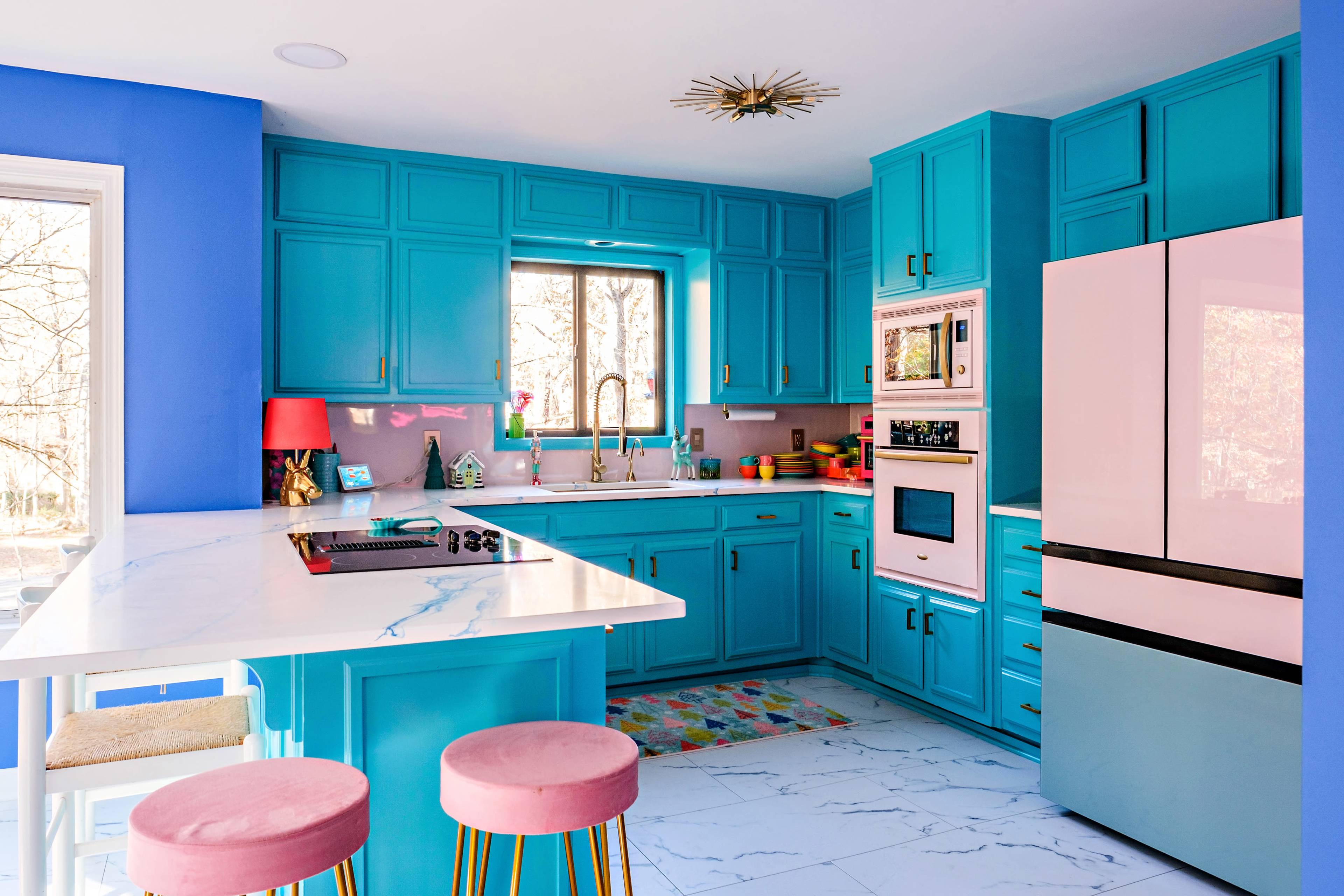 The kitchen features turquoise cabinets, a pink refrigerator, and a marble countertop with bar seating.