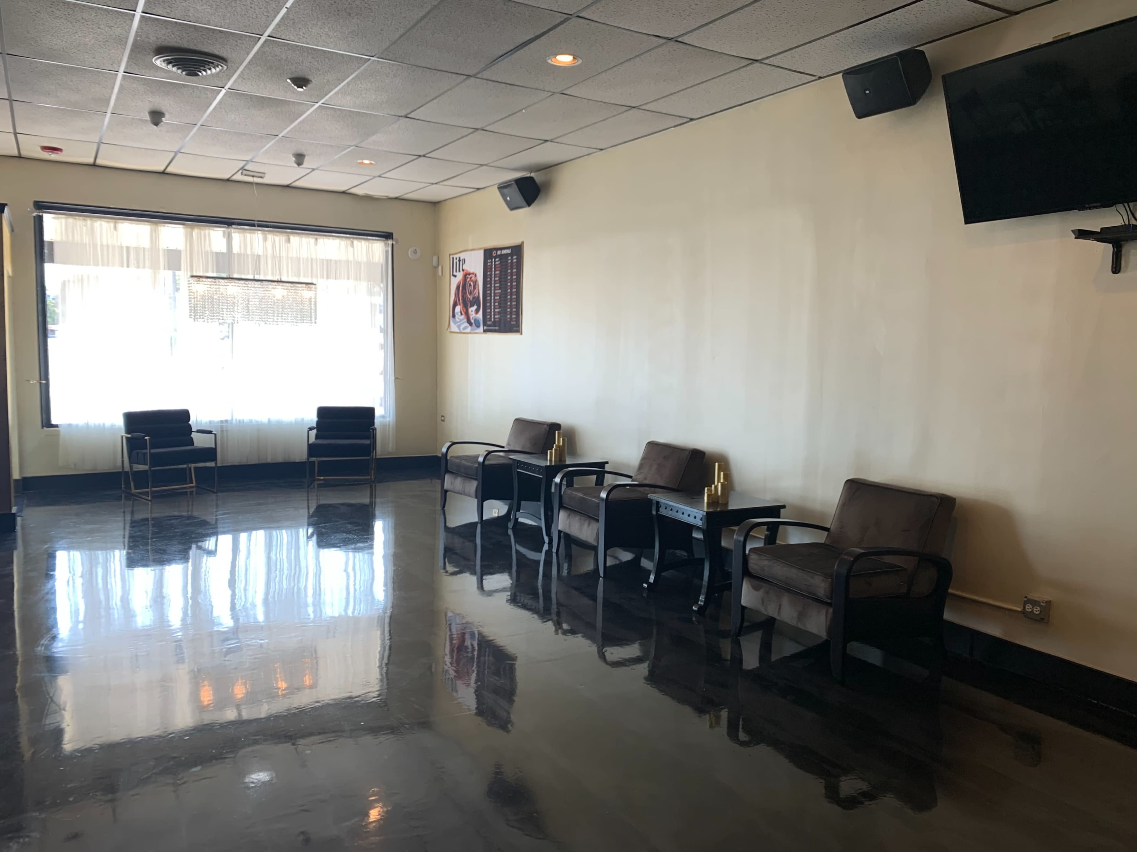 A spacious waiting area with four chairs, a table, and large windows allowing natural light to enter.