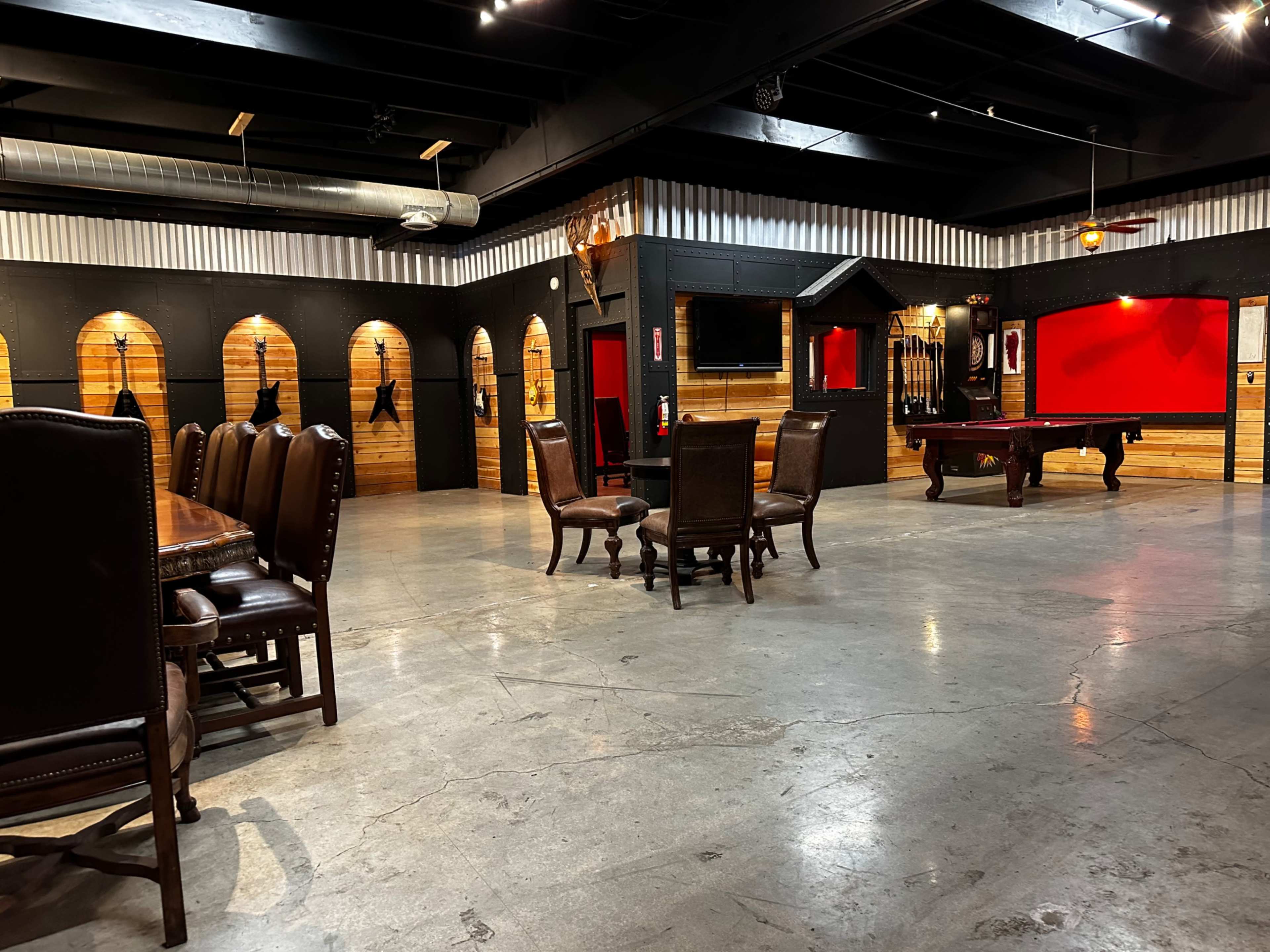 The scene features a spacious room with a dining table and chairs, surrounded by wooden walls, a pool table, and several framed items on display.