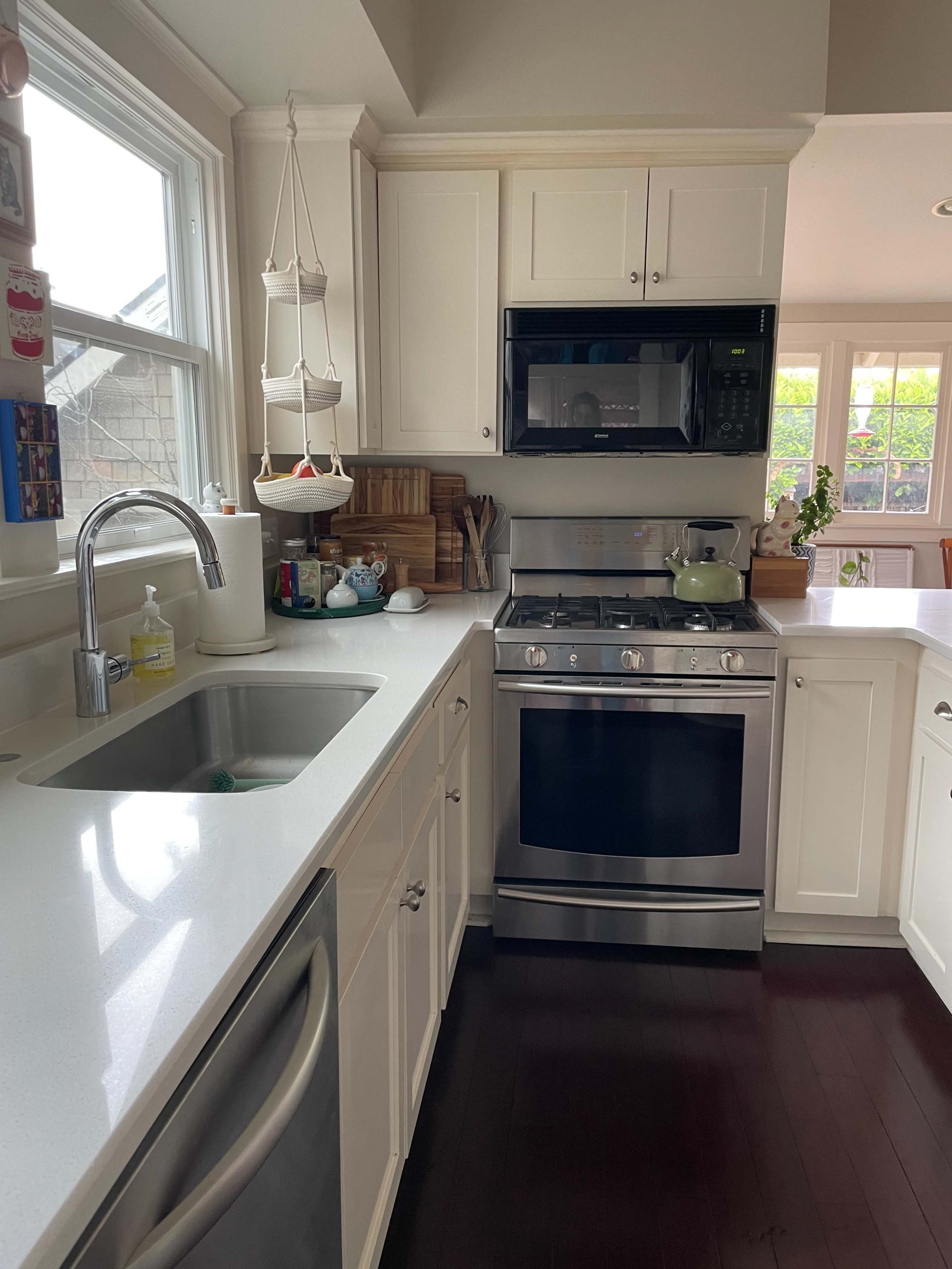 A modern kitchen featuring white cabinets, a stainless steel stove, a microwave, and a sink with a soap dispenser.