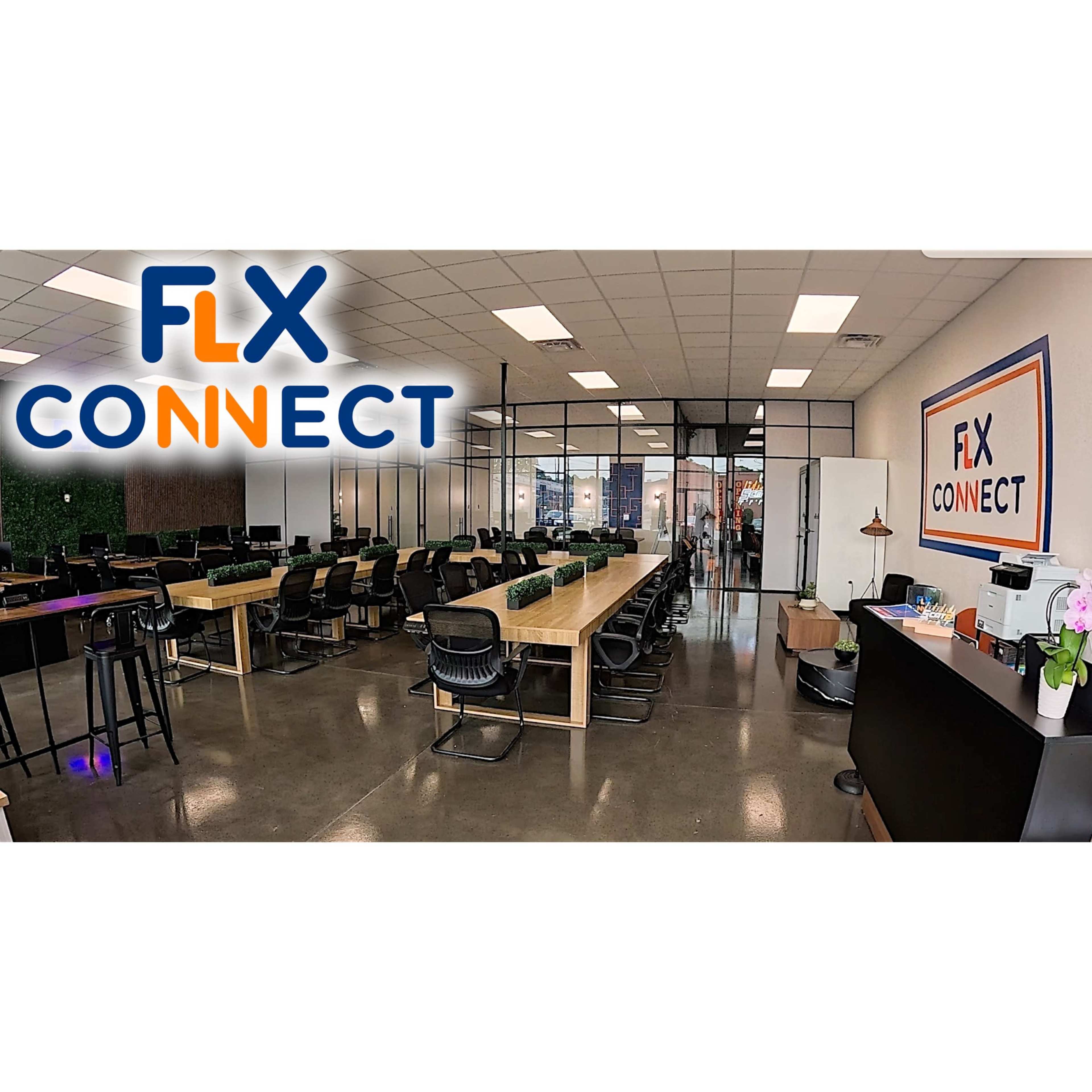 The image shows a modern office space with long wooden tables, black chairs, and clear partitions separating work areas.