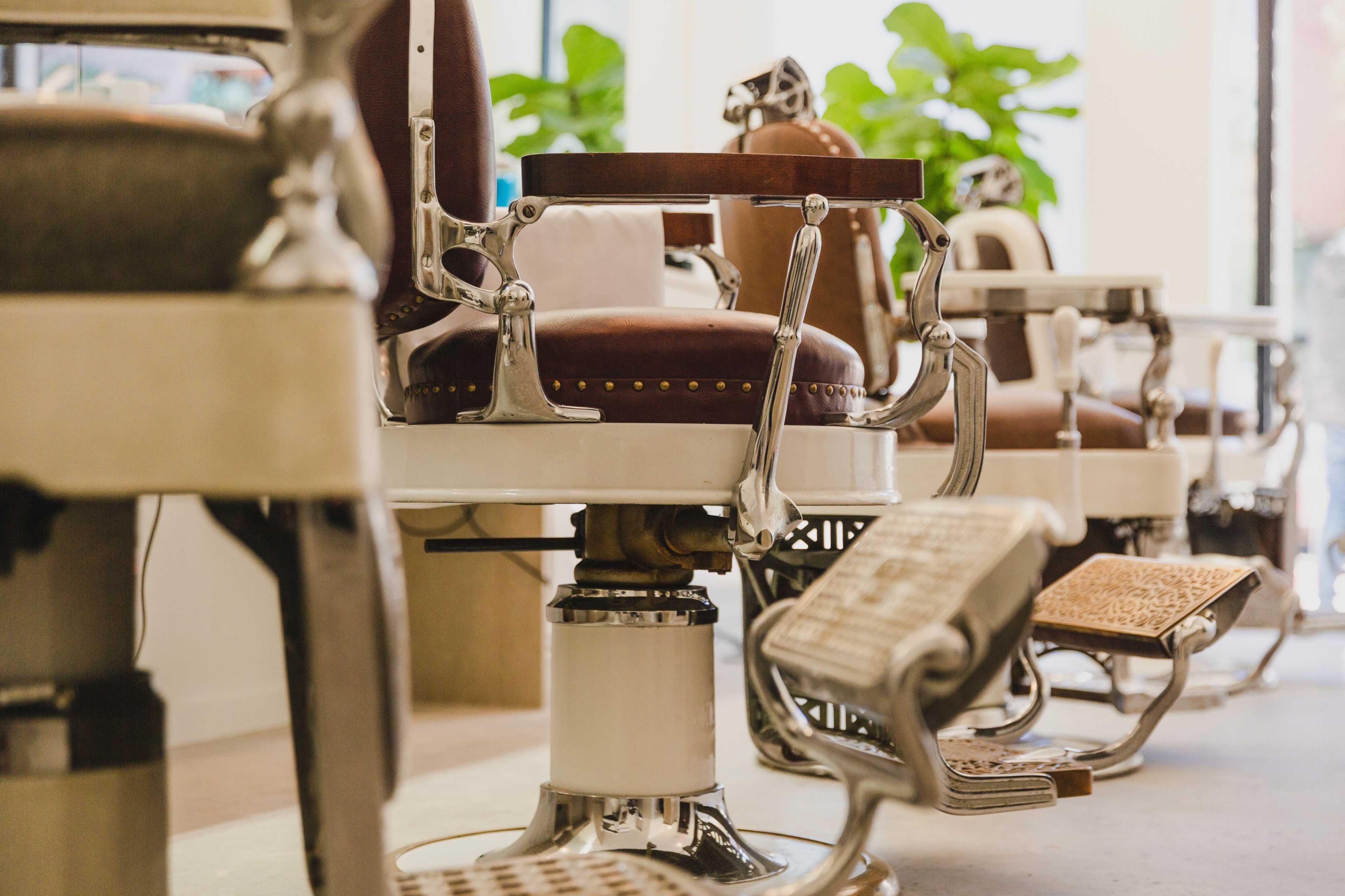 A row of vintage barber chairs arranged in a modern barber shop interior.