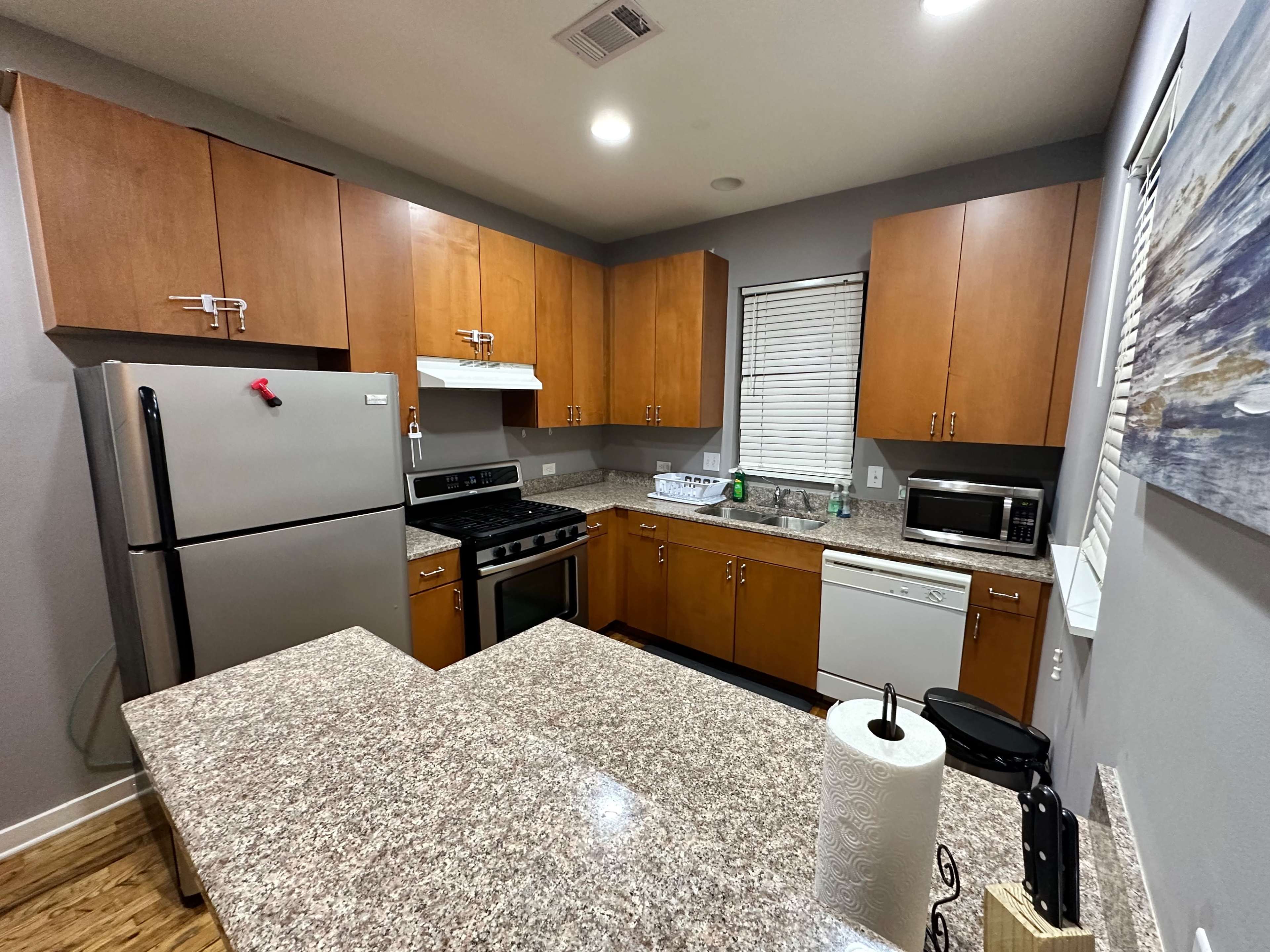 A modern kitchen with wooden cabinets, stainless steel appliances, and a granite countertop.