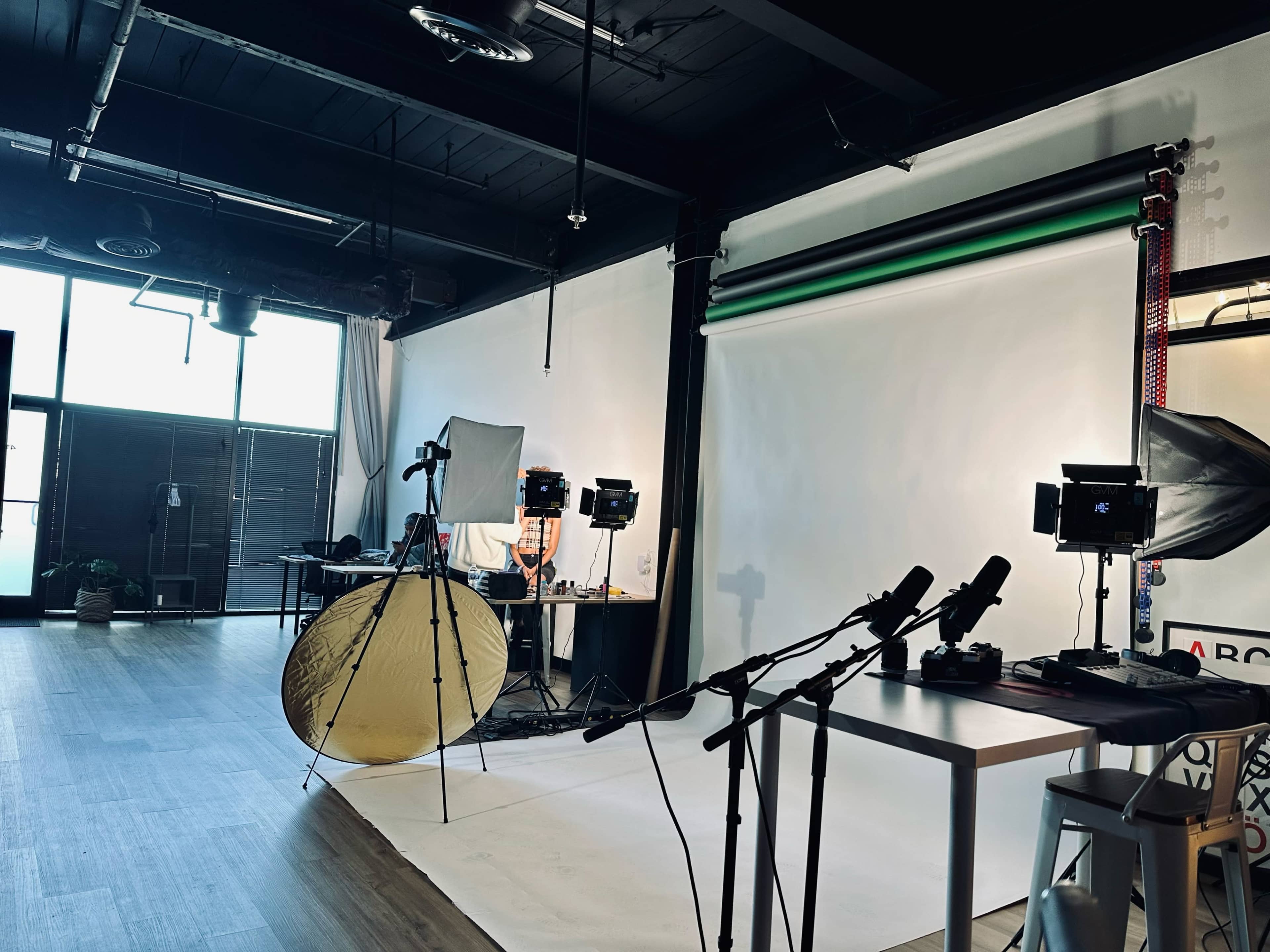 A photography studio is set up with a backdrop, lighting equipment, and audio microphones arranged for a shoot.