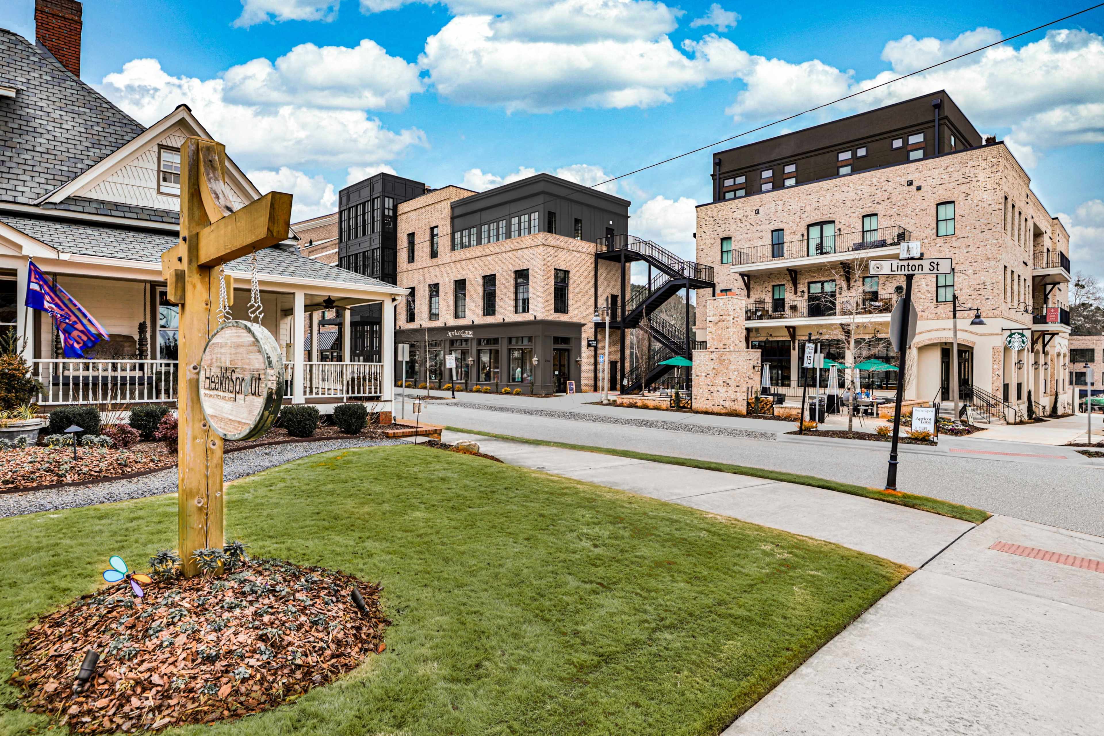 A modern mixed-use development on Linton Street, with a green lawn and a decorative sign in the foreground.