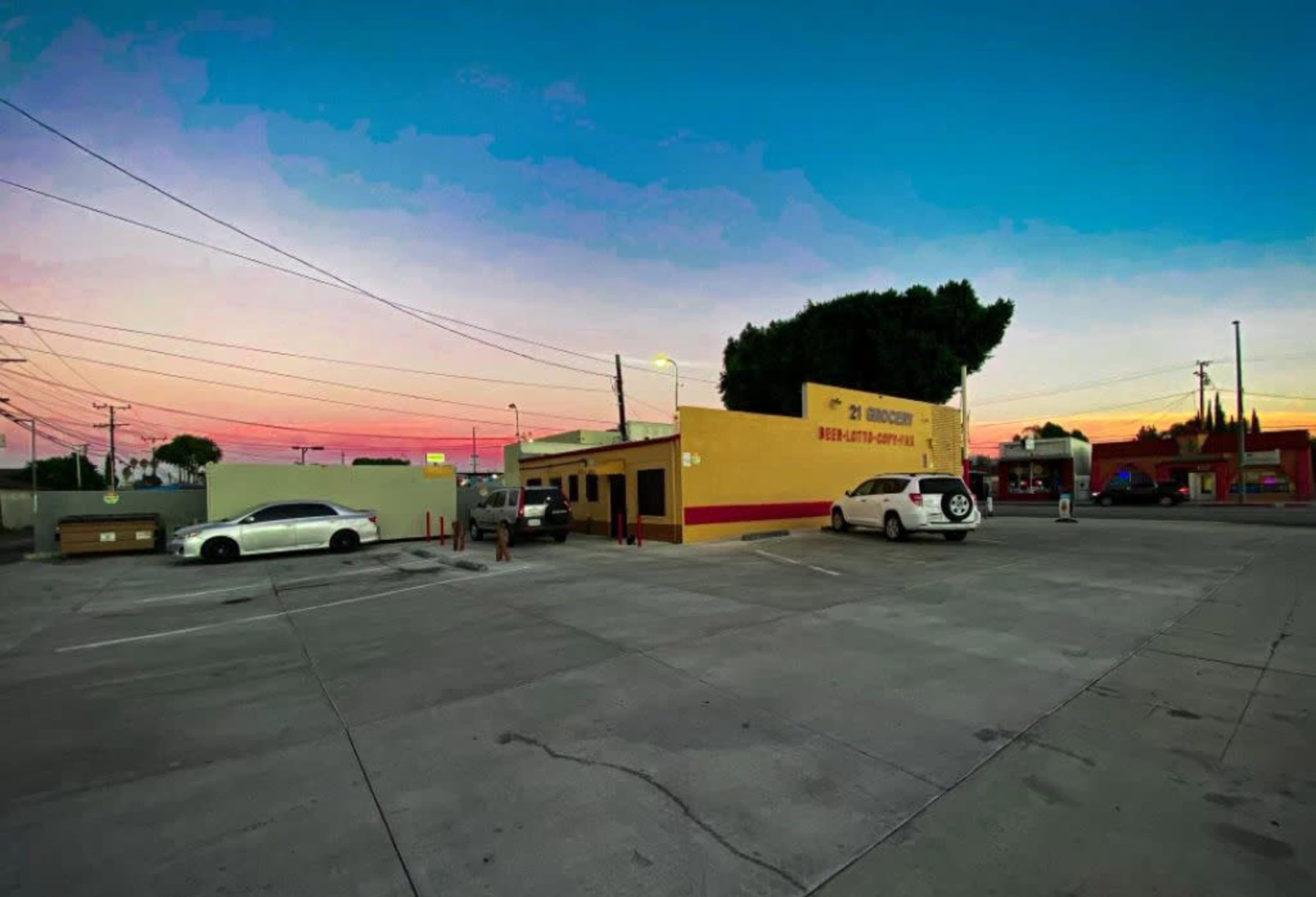 A parking lot with a small building and a vibrant sky at sunset.