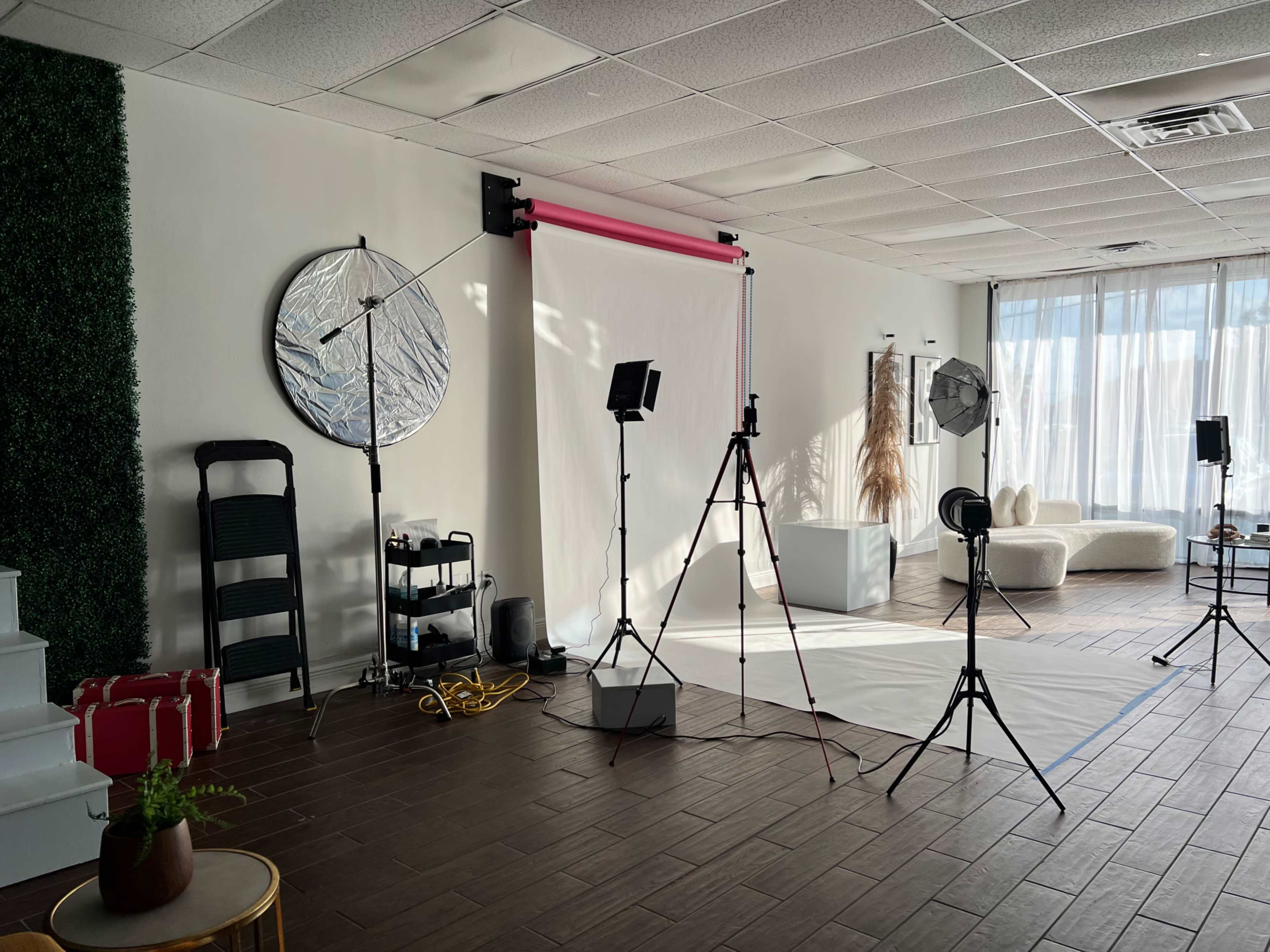 The image shows a photography studio setup with various lighting equipment, backdrops, and props arranged for a photo shoot.