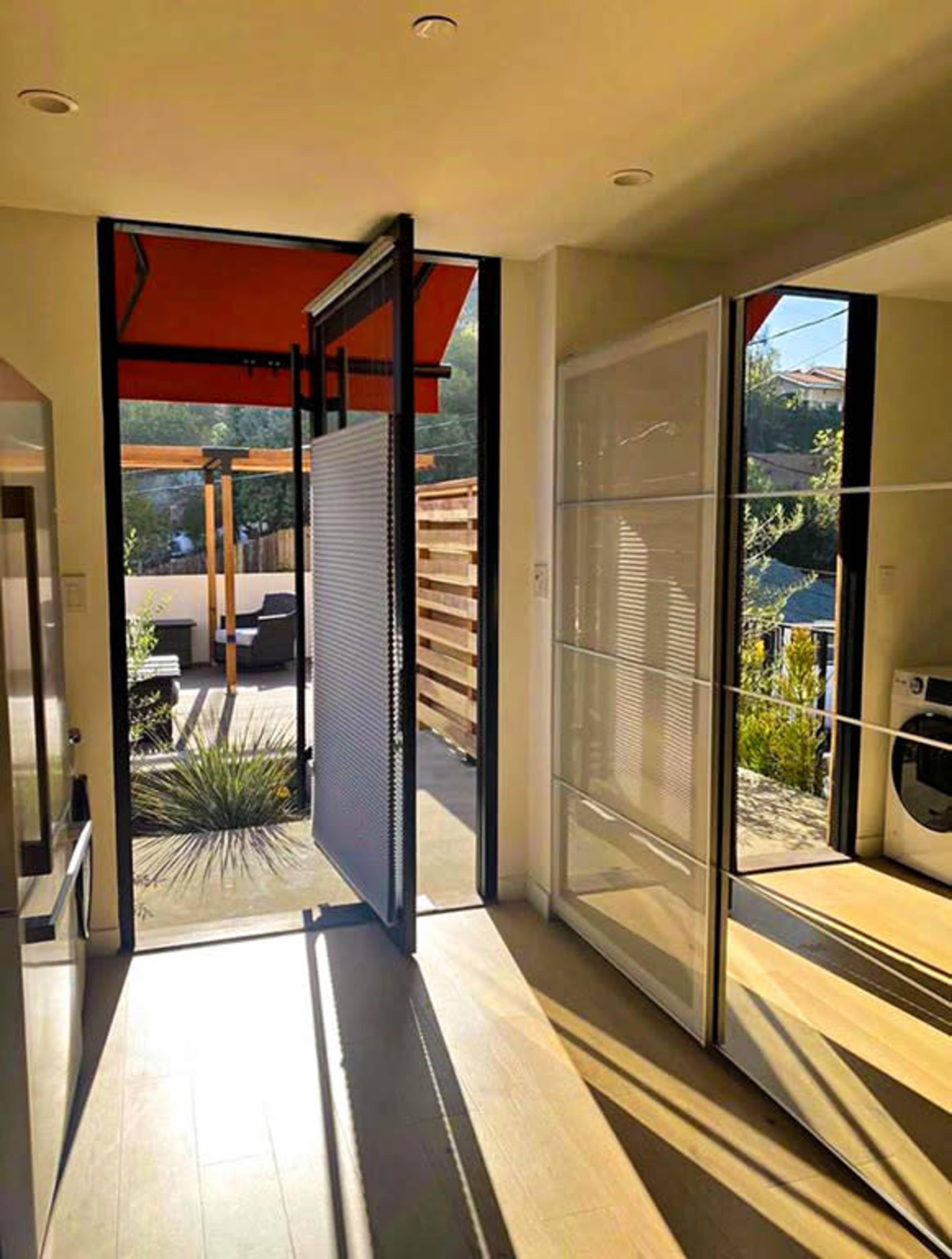 A modern interior space with a large opening that leads to an outdoor patio, illuminated by natural light.