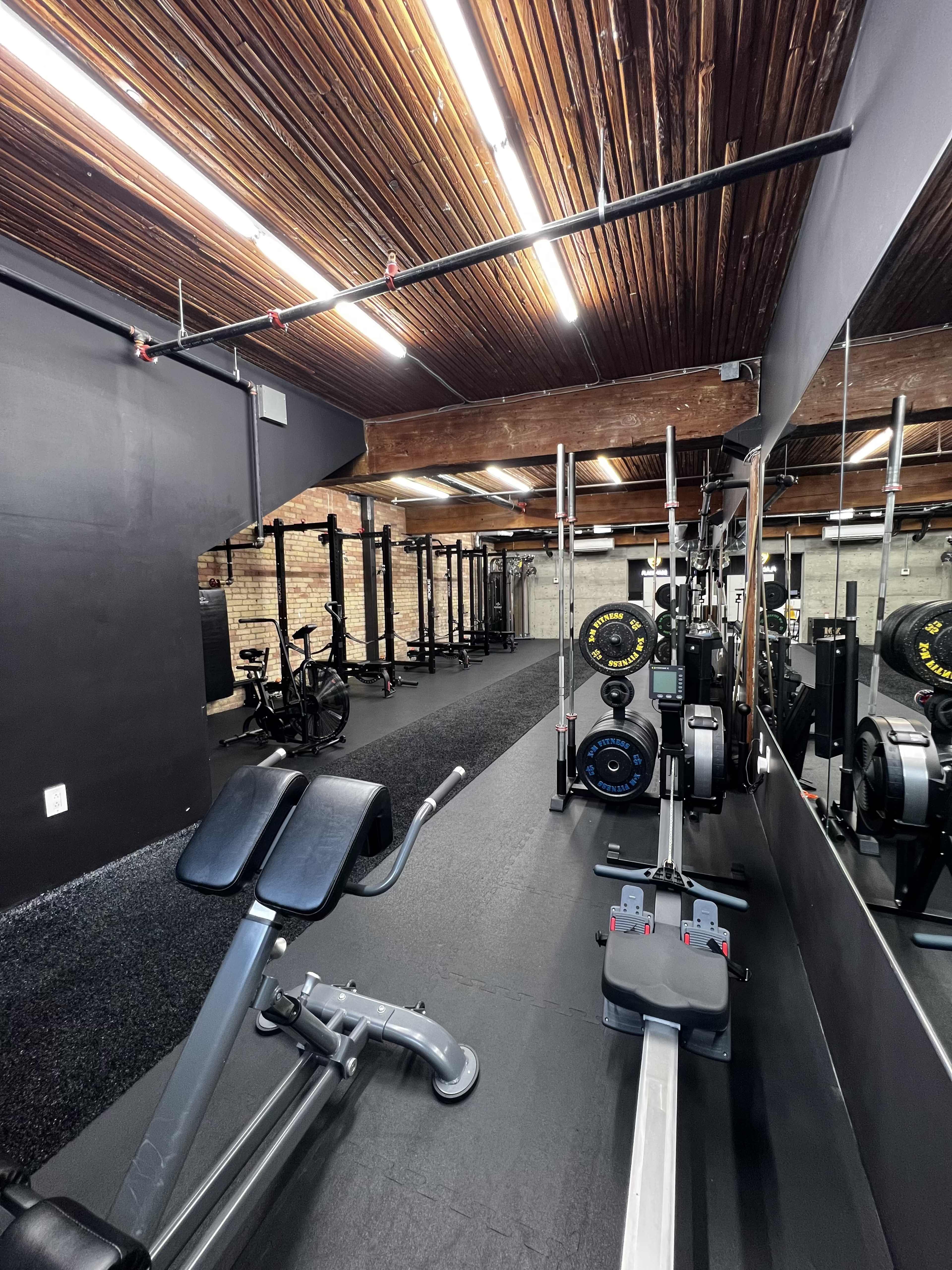 A well-equipped gym with exercise machines, free weights, and mirrors along one wall.