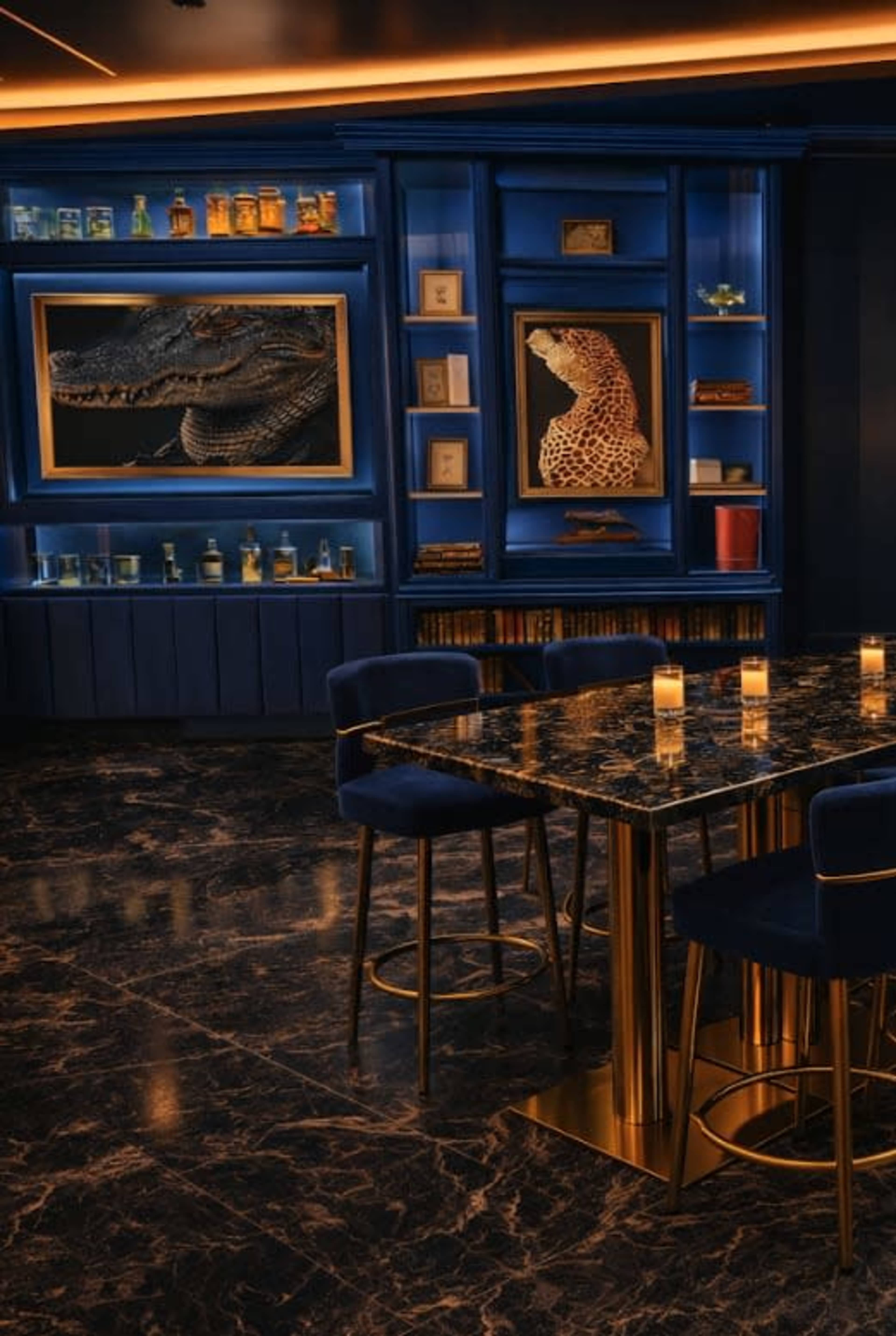 The interior of a bar features dark marble flooring, a gold-accented table with blue chairs, and a wall display showcasing a crocodile and a giraffe sculpture against a blue background.