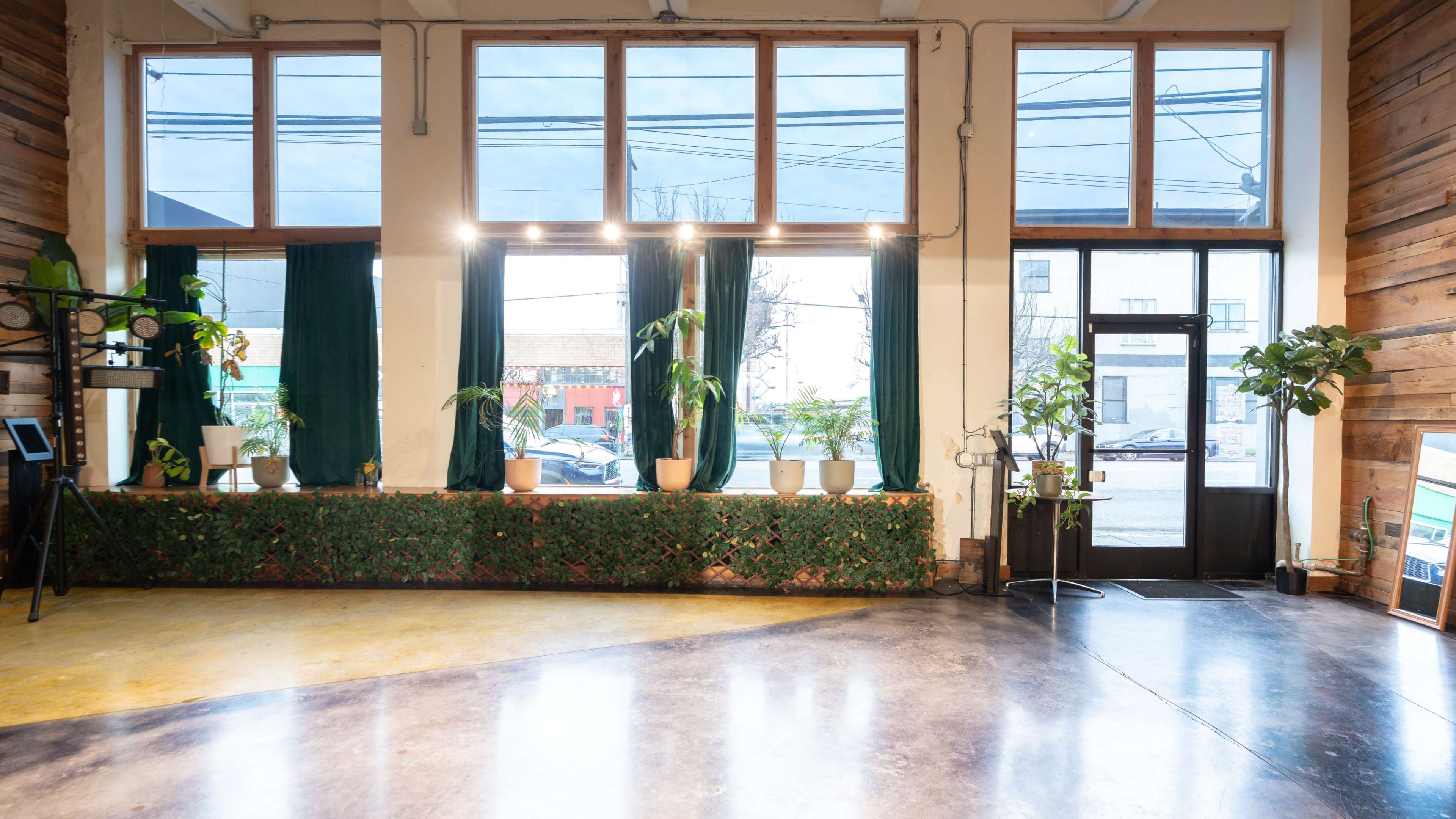 The image shows an indoor space with large windows, potted plants on a ledge, and a doorway leading outside.