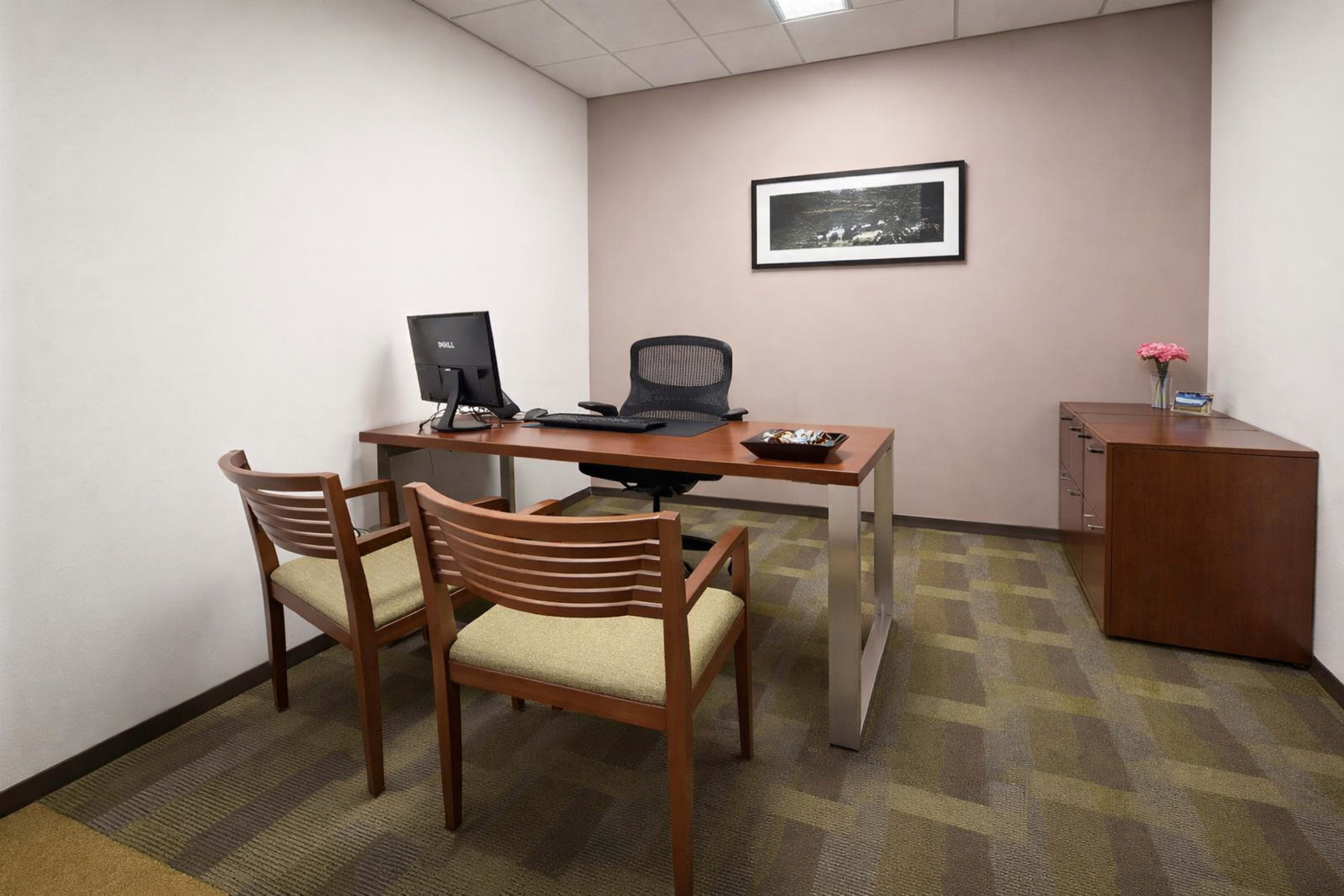 The image shows a small office space featuring a desk with a computer, two chairs, and a cabinet along one wall.