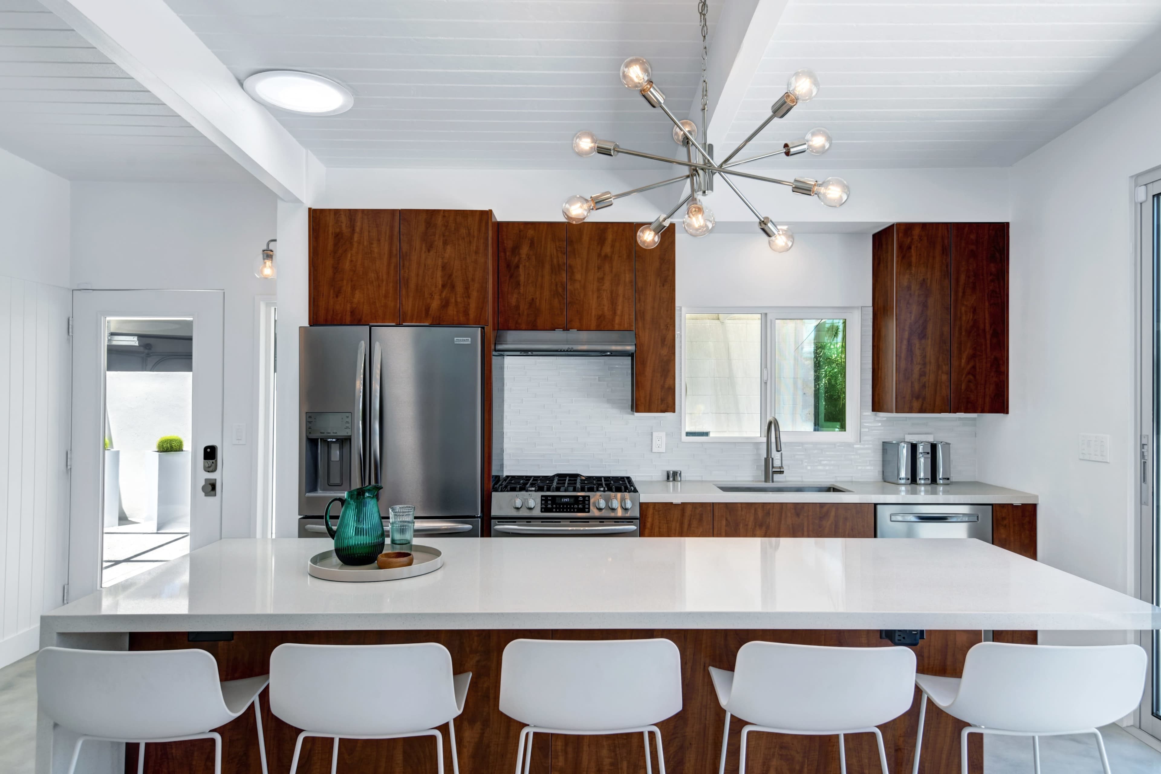 A modern kitchen features a large island with seating, stainless steel appliances, and wooden cabinetry.