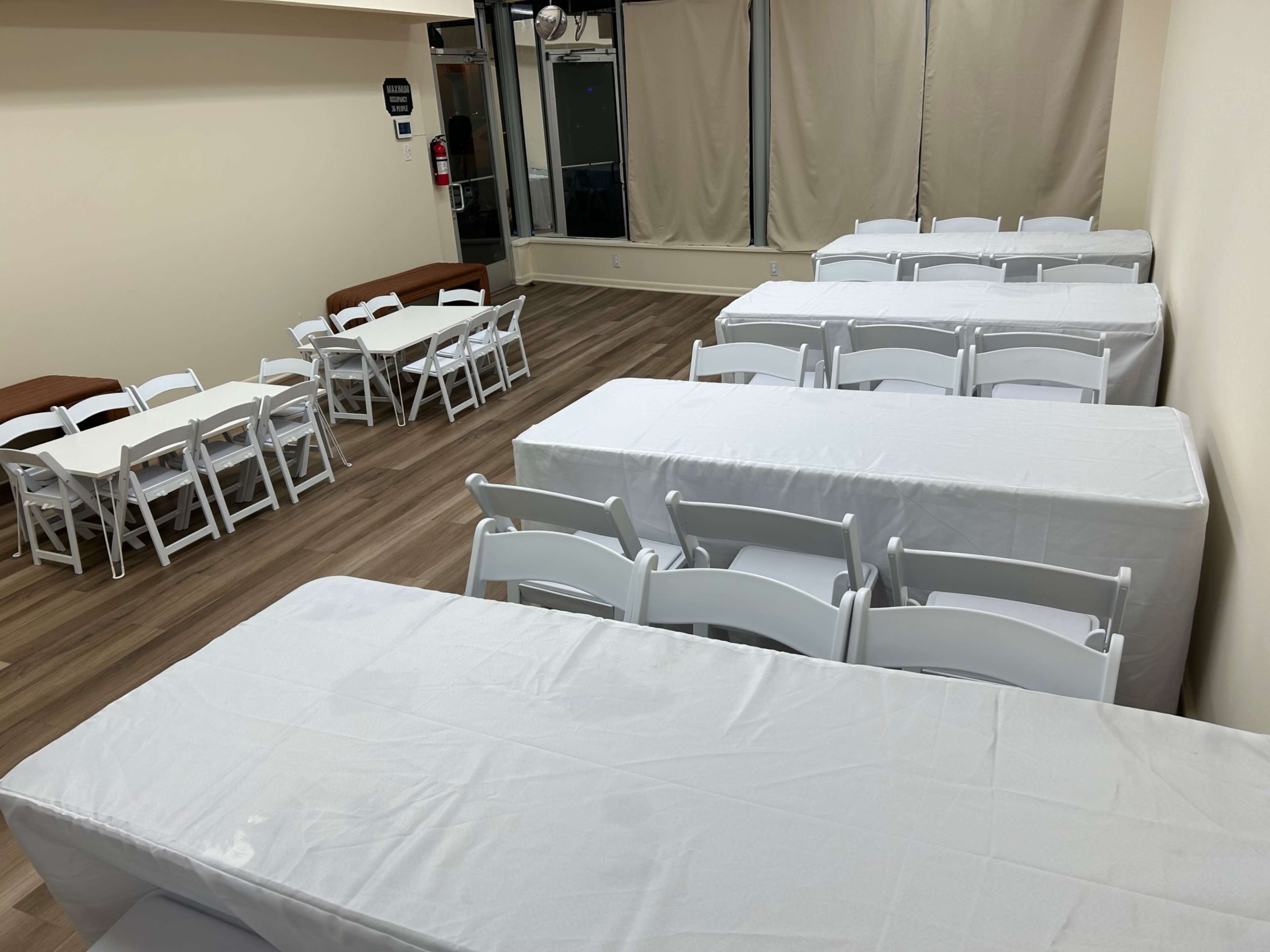 The room contains several tables covered with white tablecloths, arranged in a semi-open layout with a few chairs placed around them.