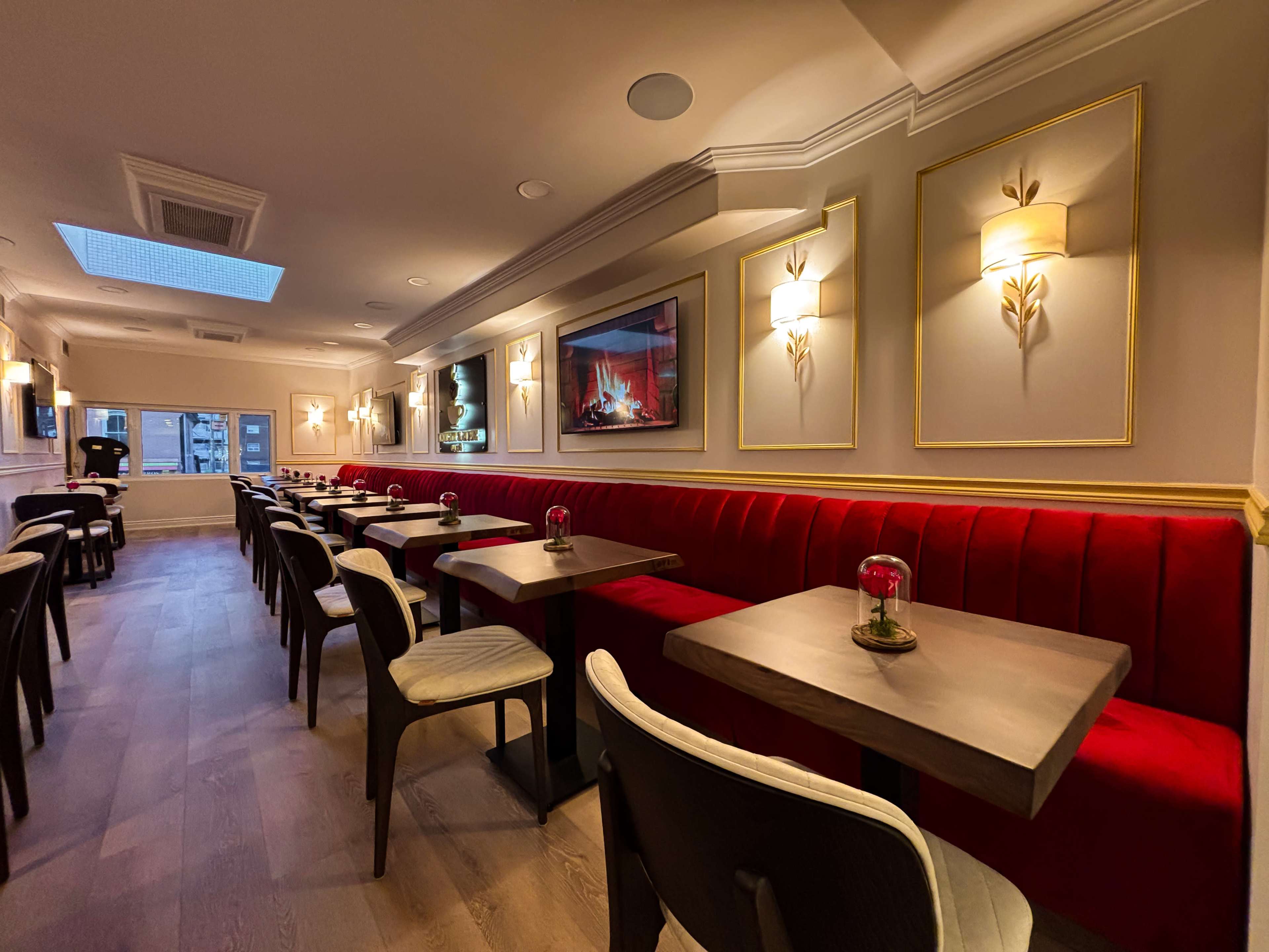 The image shows a modern restaurant interior featuring red booth seating, wooden tables, and decorative wall lighting.