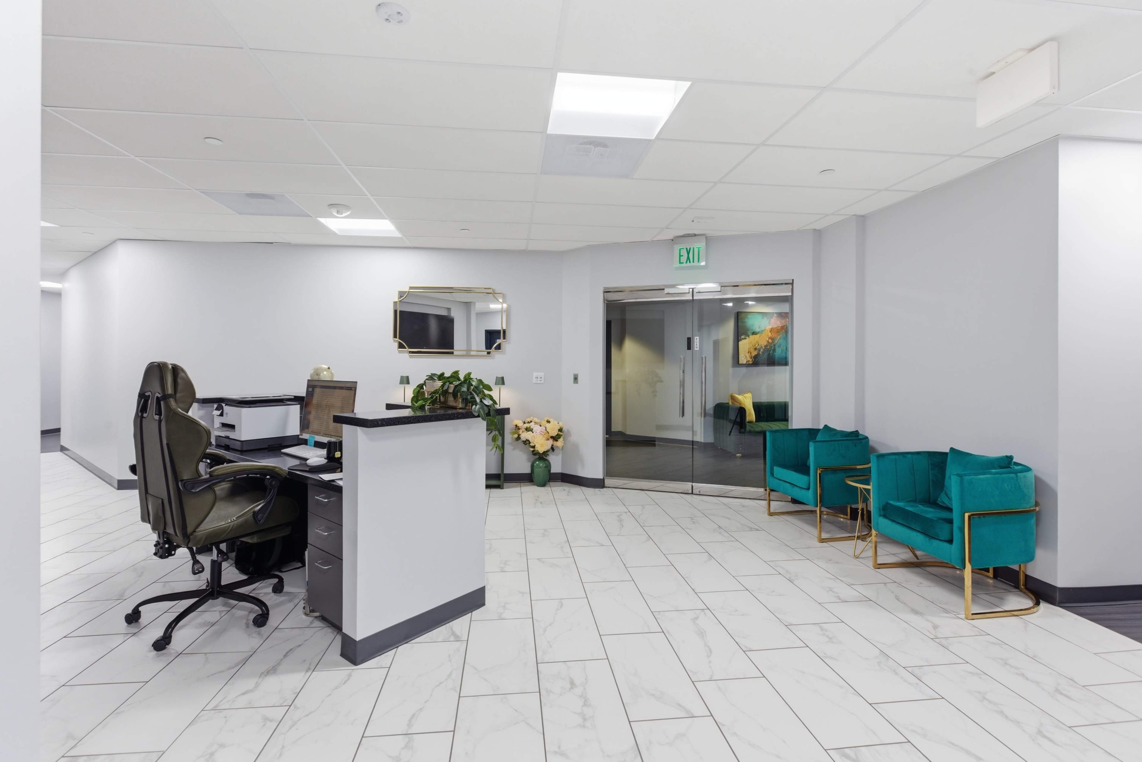 The image shows a modern office reception area with a desk, chairs, and a glass entrance.