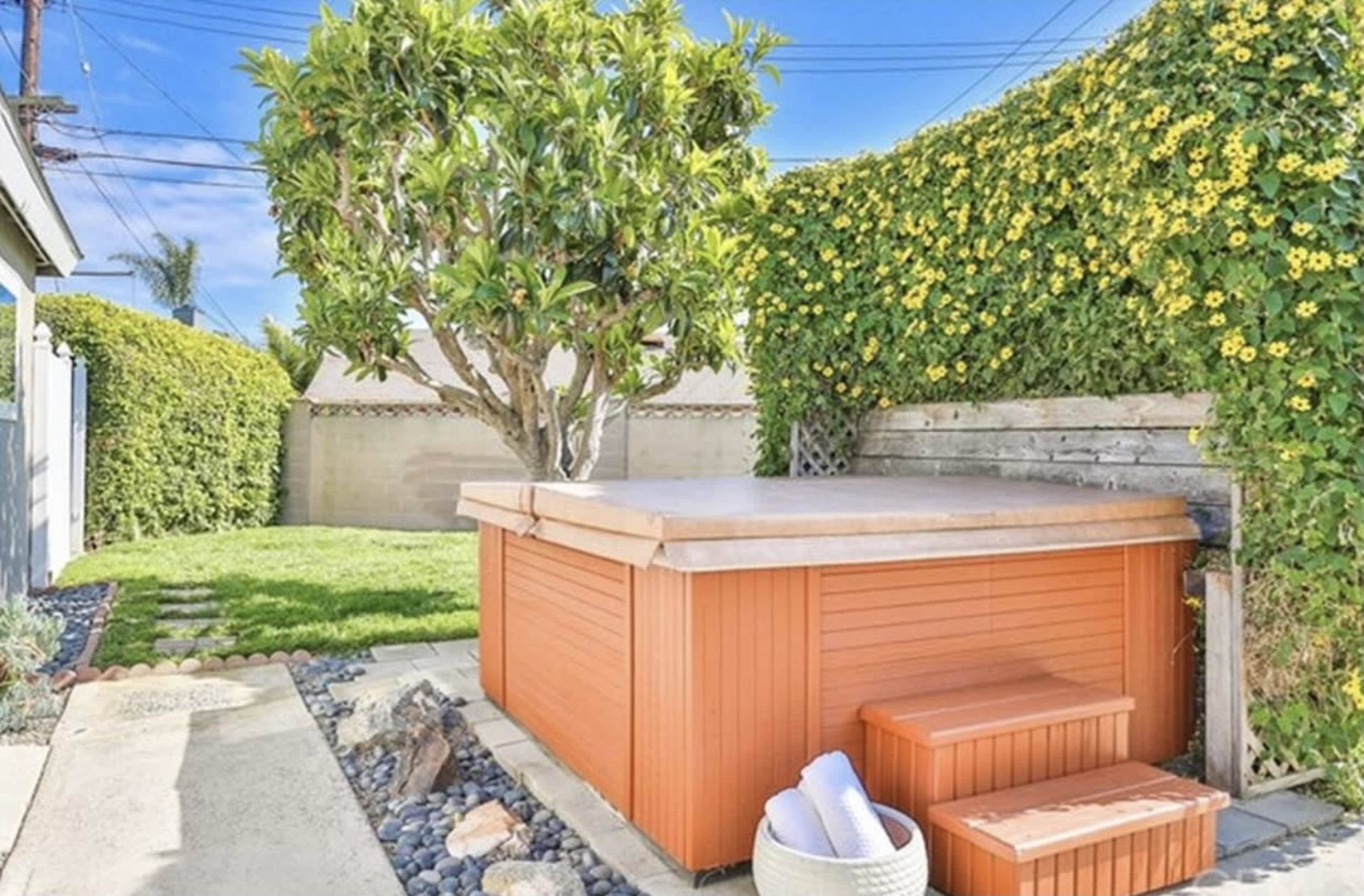 A hot tub surrounded by lush greenery and a neatly landscaped yard.