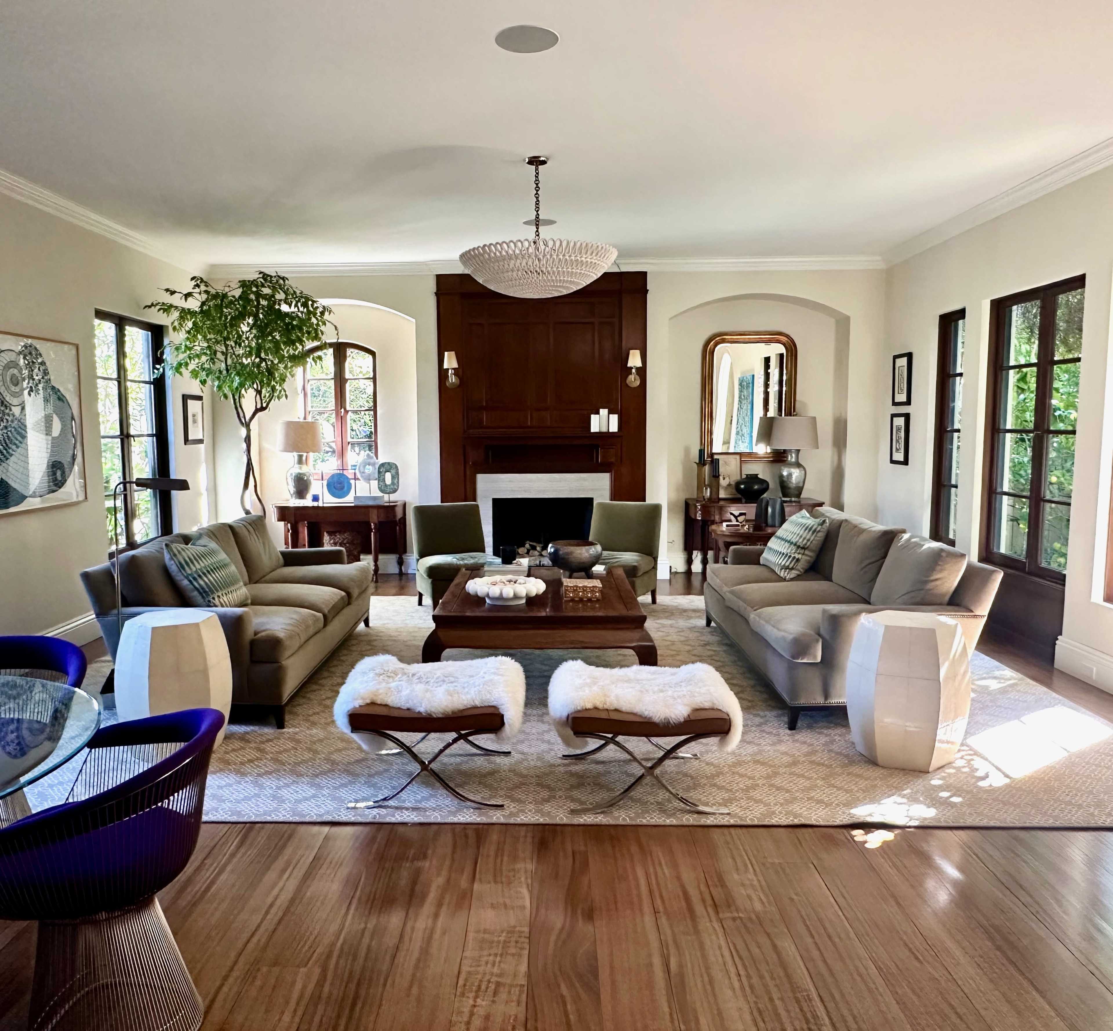 The image shows a spacious living room with a modern design, featuring two sofas, a coffee table, and large windows that allow natural light to illuminate the space.