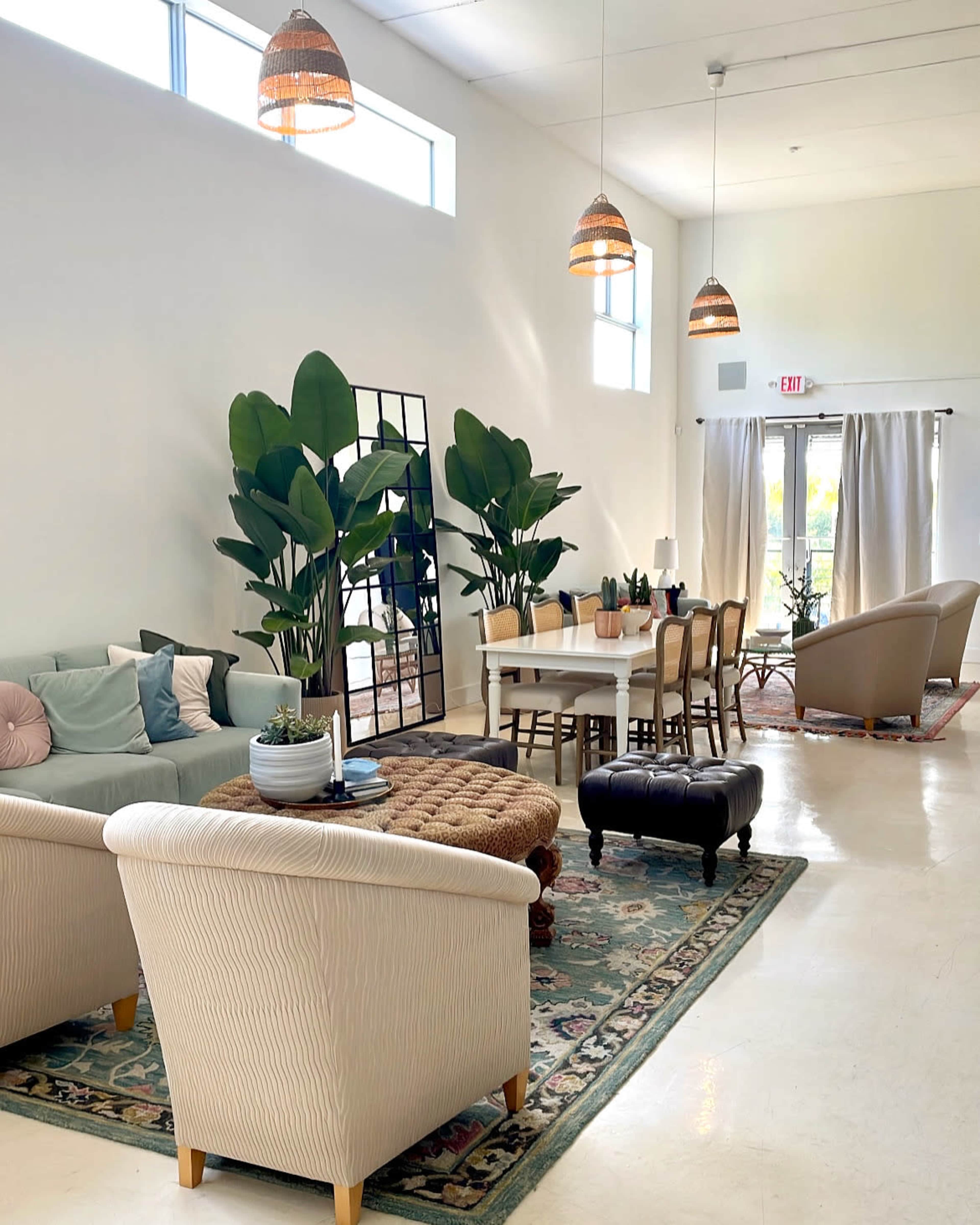 A bright, modern living space with a dining area, comfortable seating, and large indoor plants.