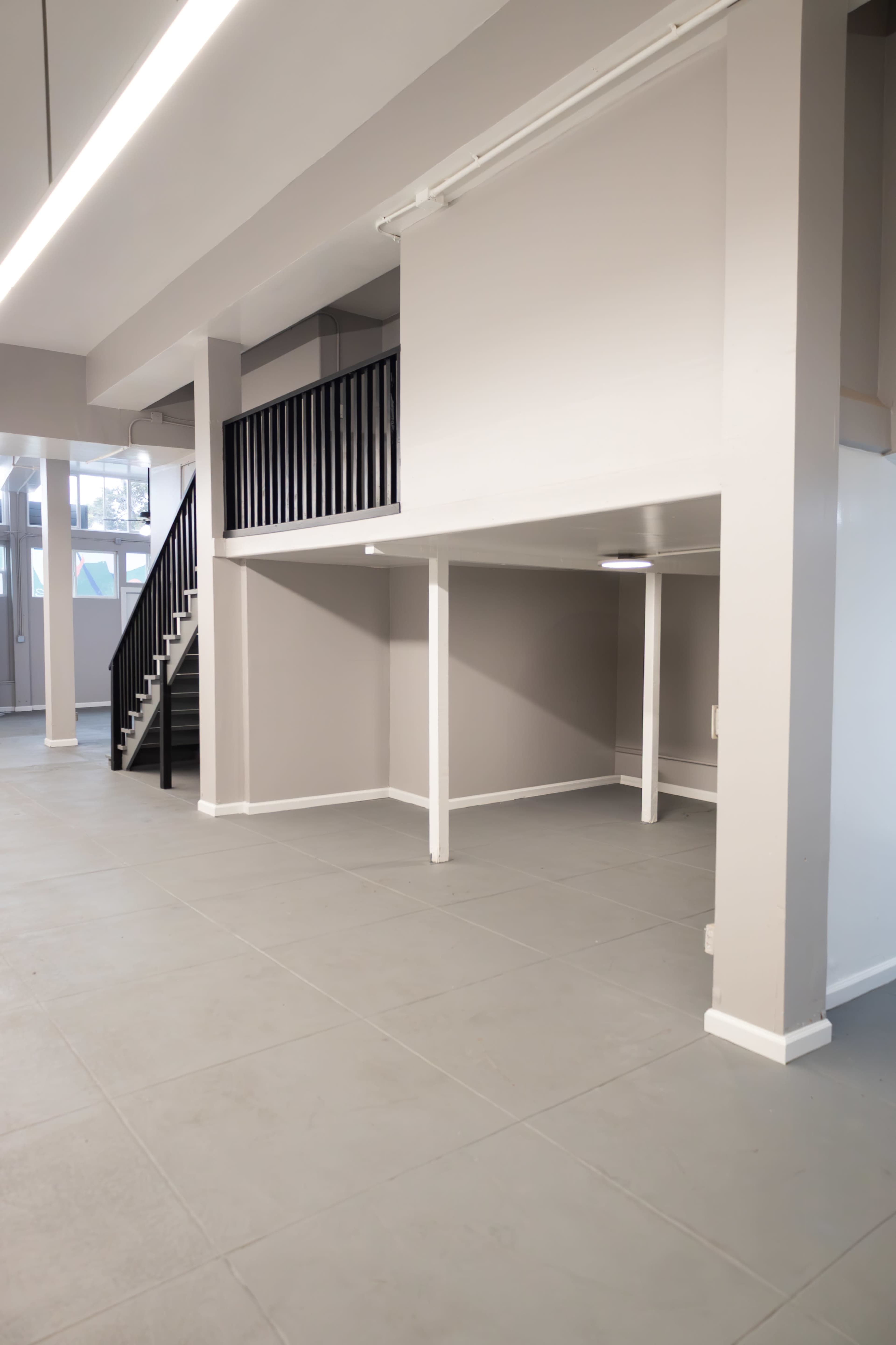 The image shows an interior space featuring a two-level layout with a staircase and gray tiled flooring.