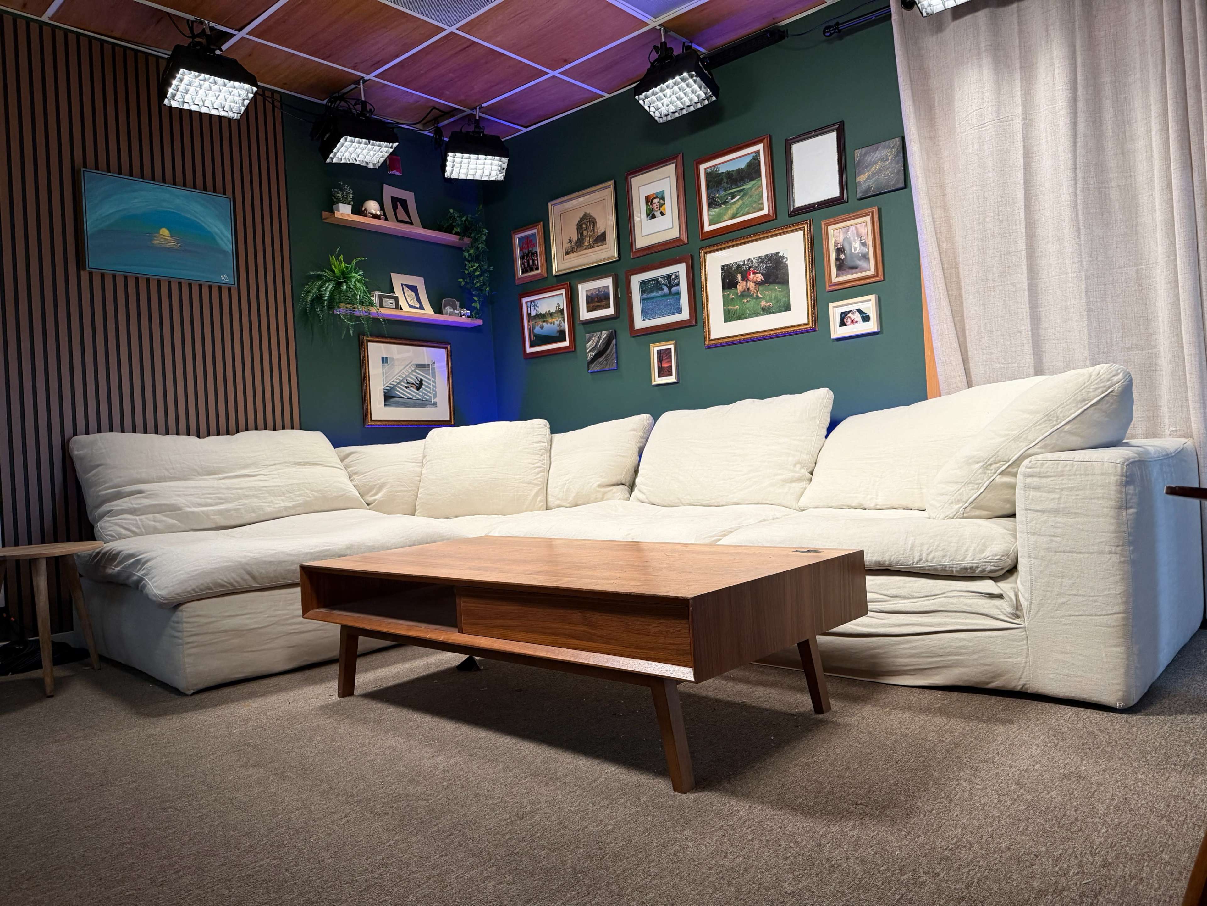 The image shows a cozy living room setting with a large white sectional sofa, a wooden coffee table, and decorative framed photos on the wall.