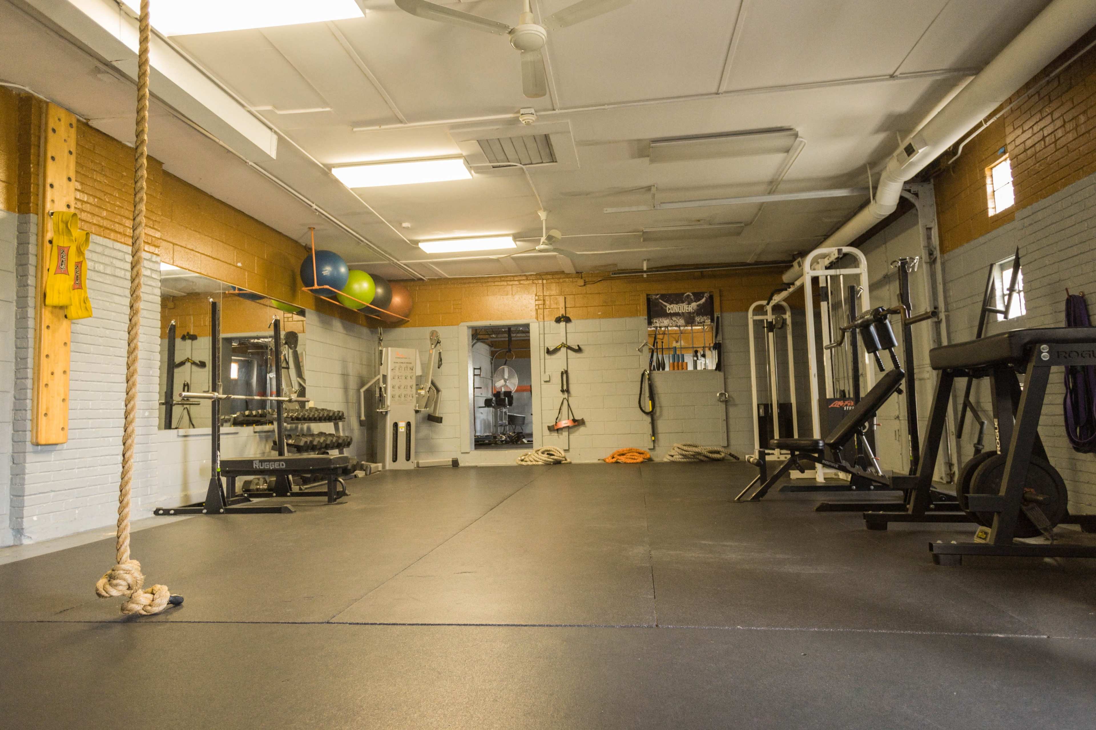A spacious gym interior with equipment including weight machines, a mirror, and exercise balls.