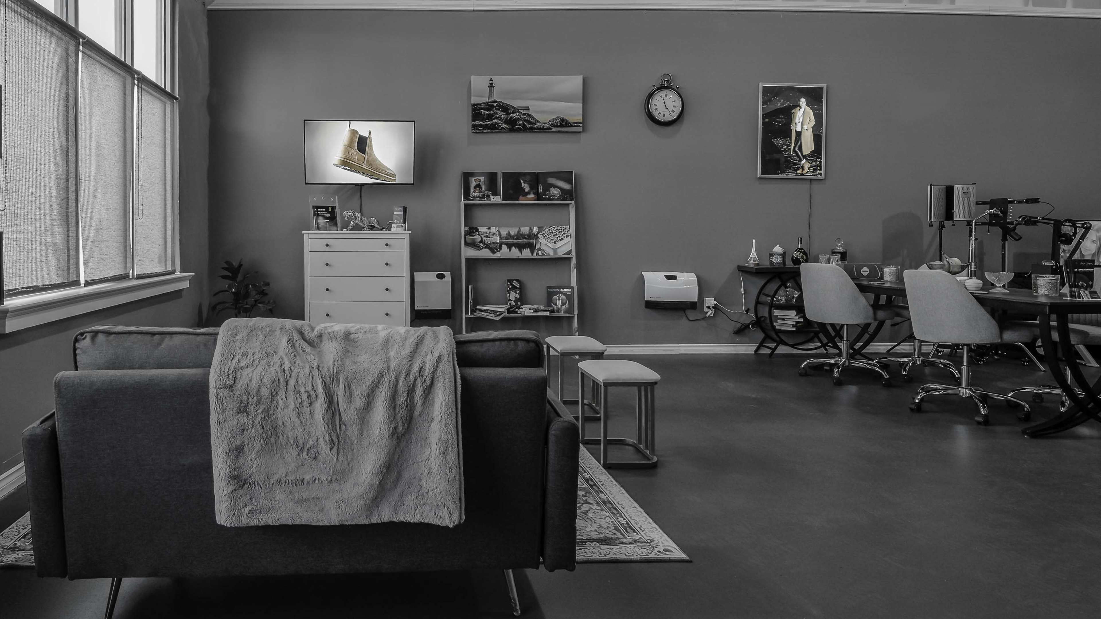 A cozy, modern office space features a dark sofa, a small coffee table, and shelves displaying various items against a gray wall.