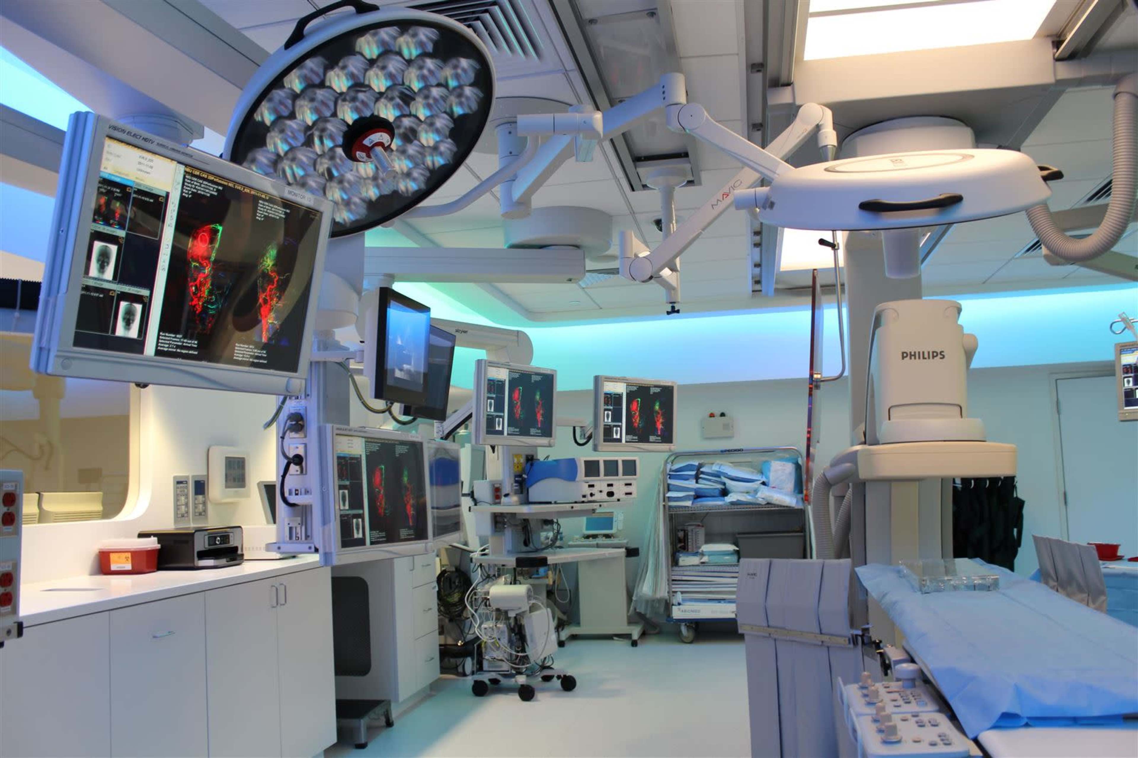 A modern surgical operating room equipped with advanced medical technology, including multiple monitors and surgical lighting.