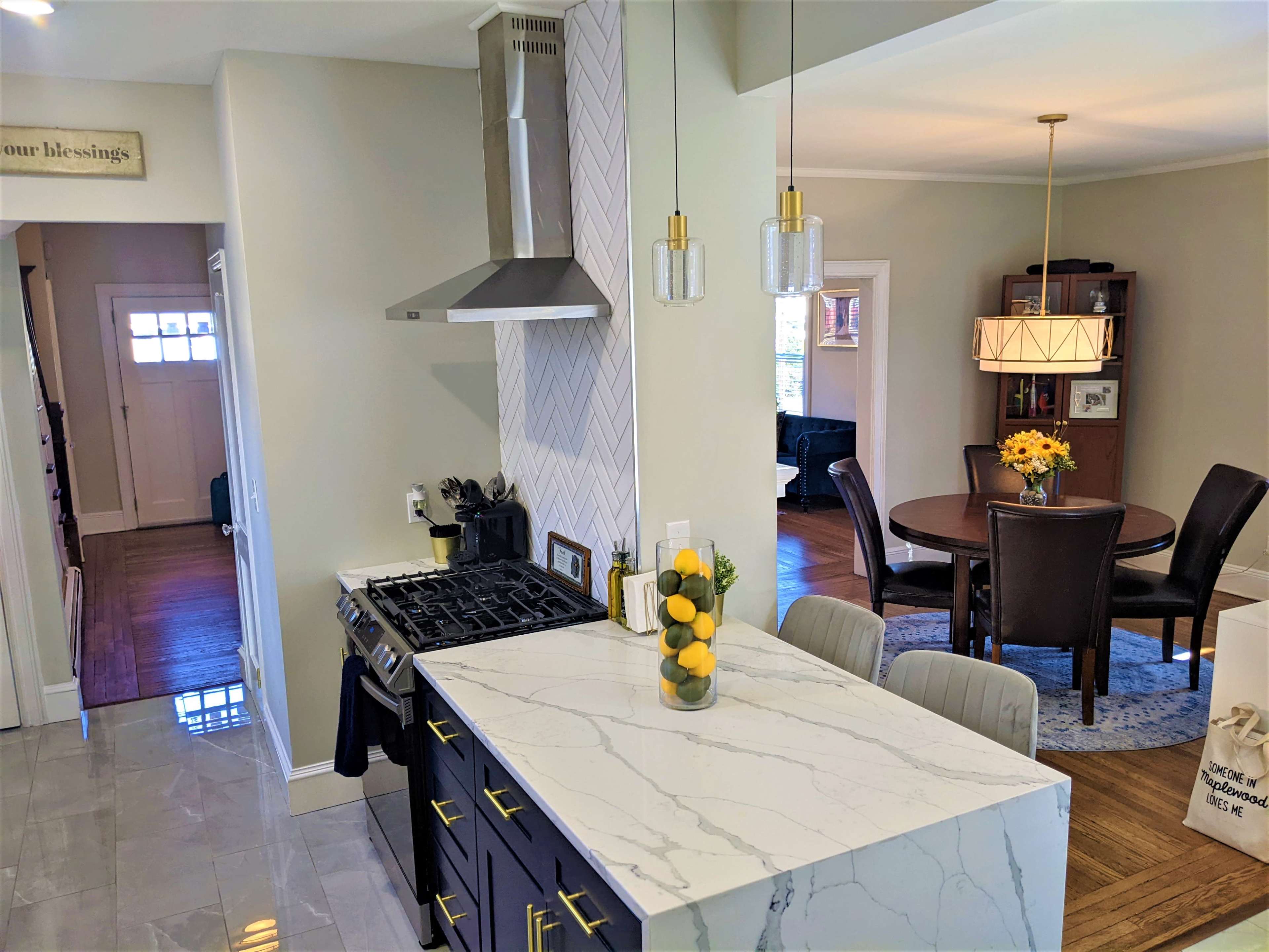 A modern kitchen with a gas stovetop, a marble countertop adorned with lemons, and a dining area visible in the background.