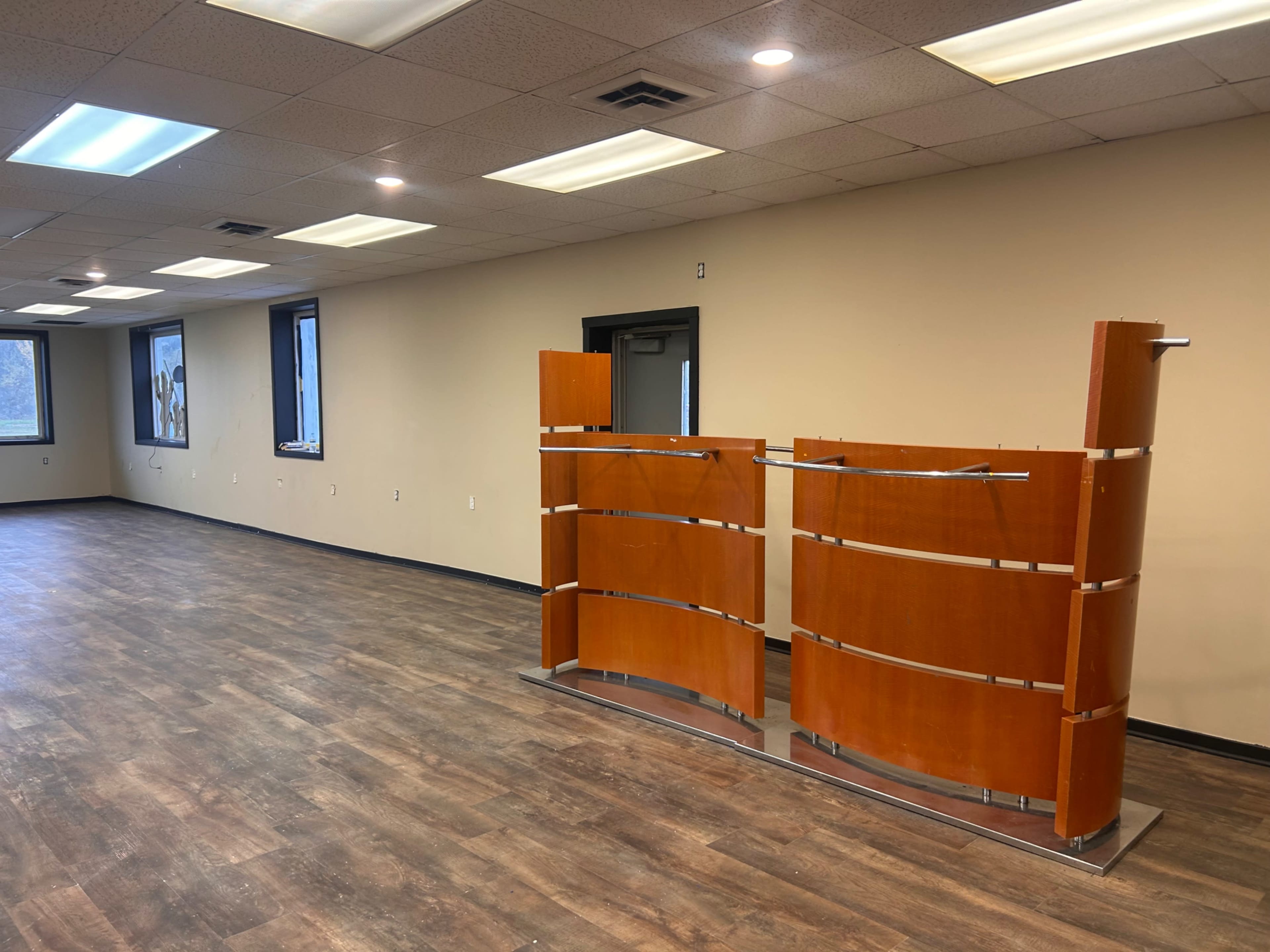 The image shows a spacious, empty office interior with a wooden reception desk positioned in the center.