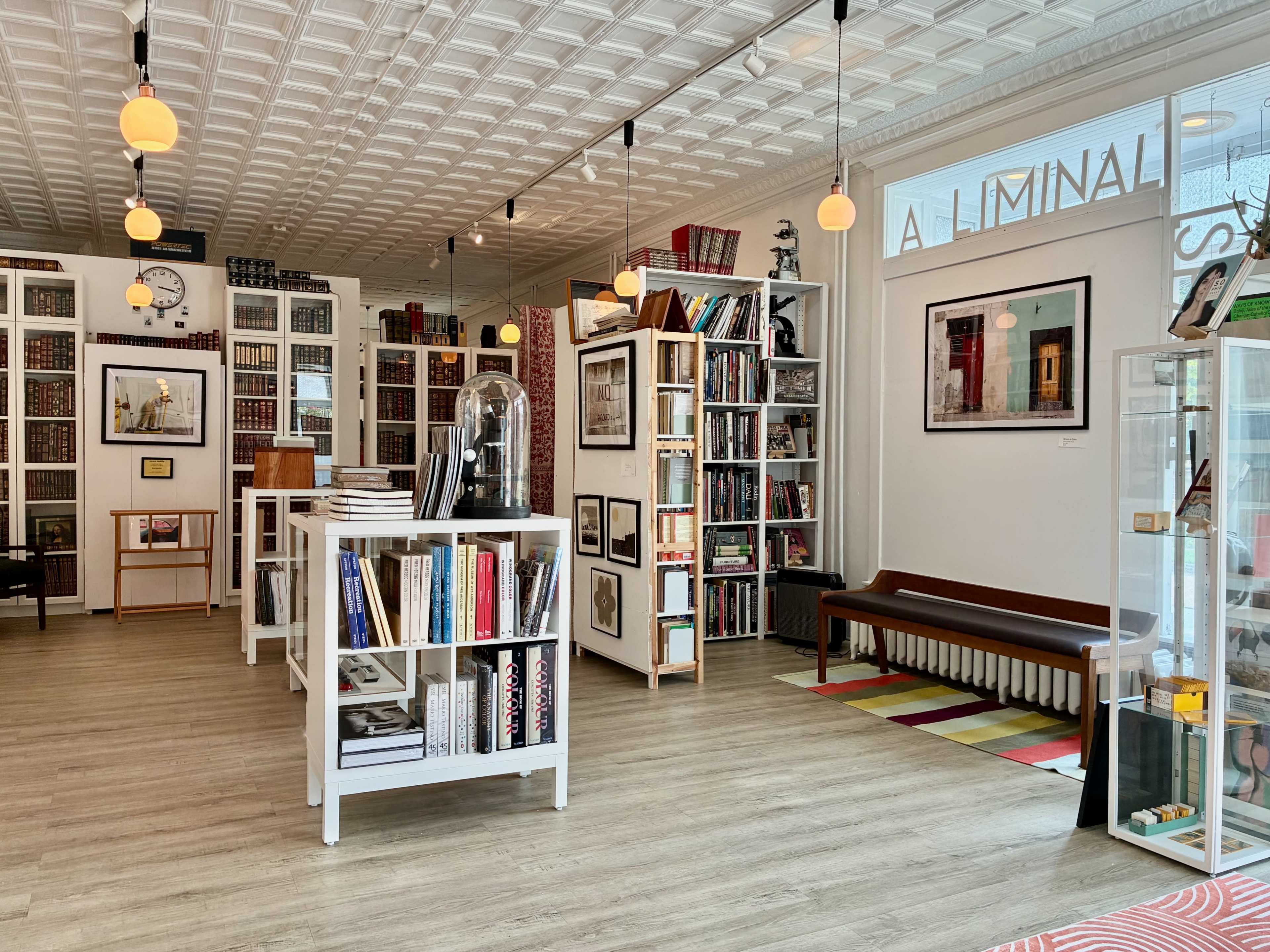 The interior of a stylish bookstore features bookshelves filled with books, artwork on the walls, and cozy seating areas.