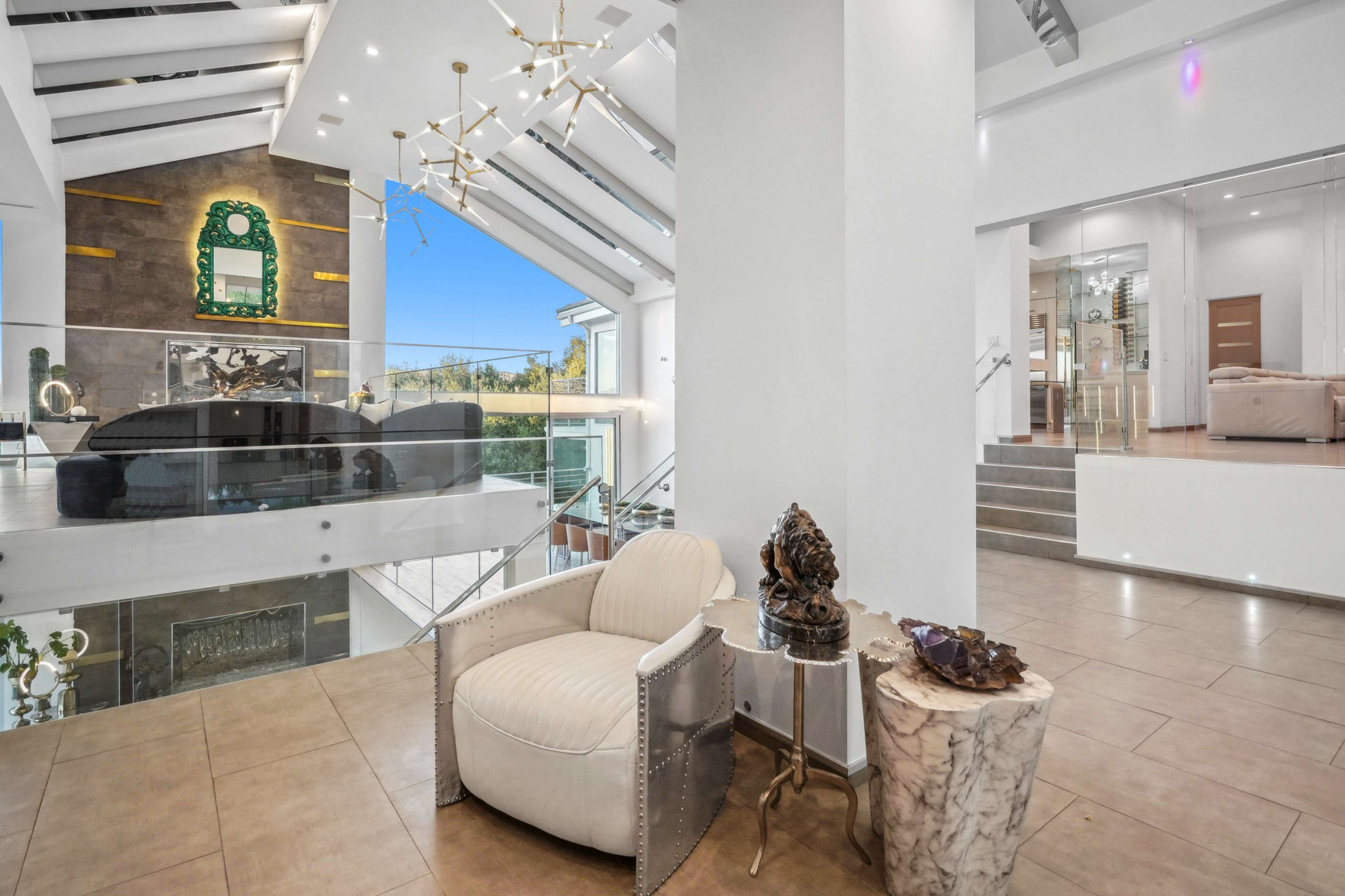 The image features a modern interior space with high ceilings, a glass railing overlooking a multi-level area, and stylish furniture elements.