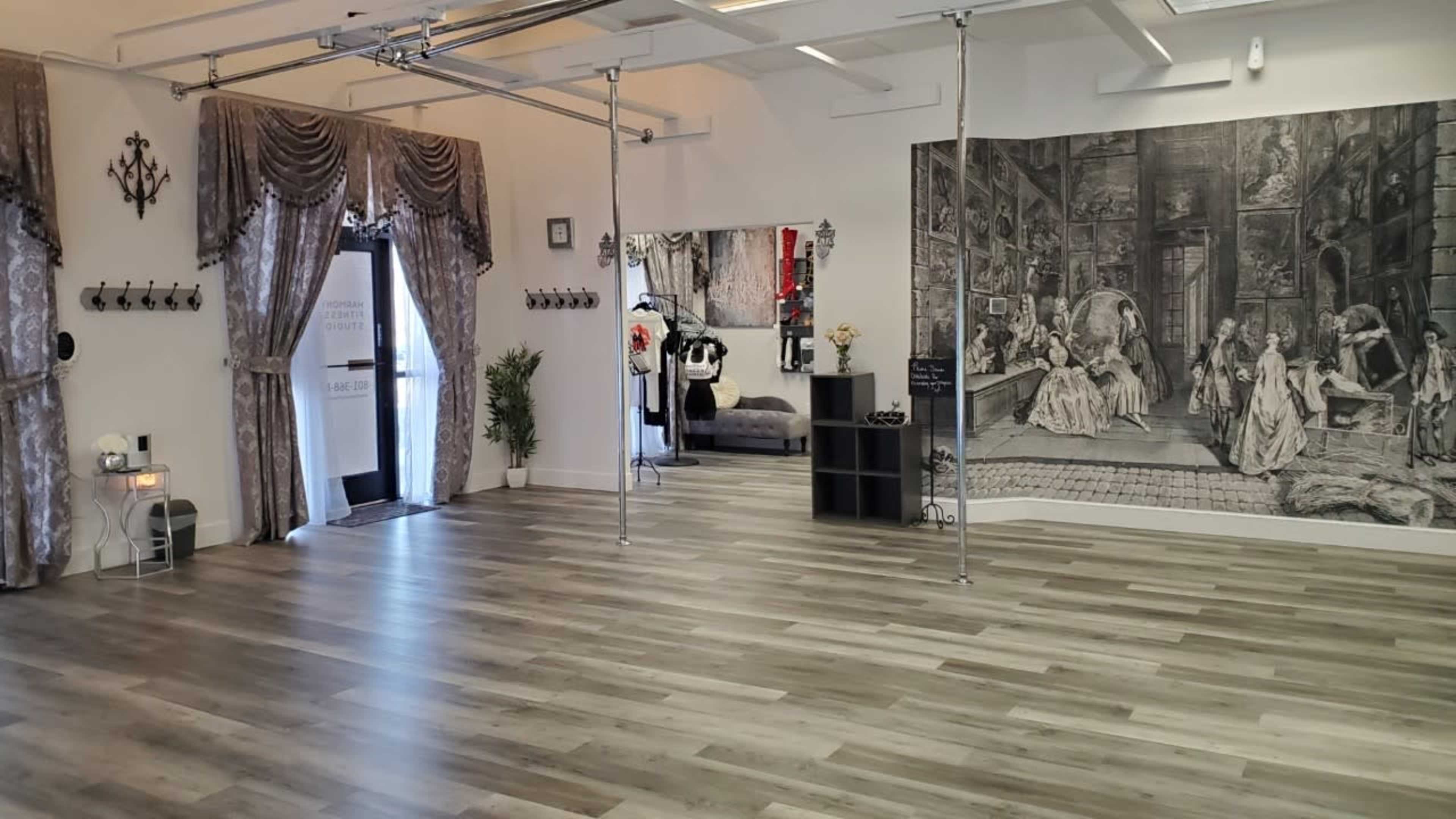 An interior space with wooden floors, draped curtains, and a large mural depicting historical figures on one wall.