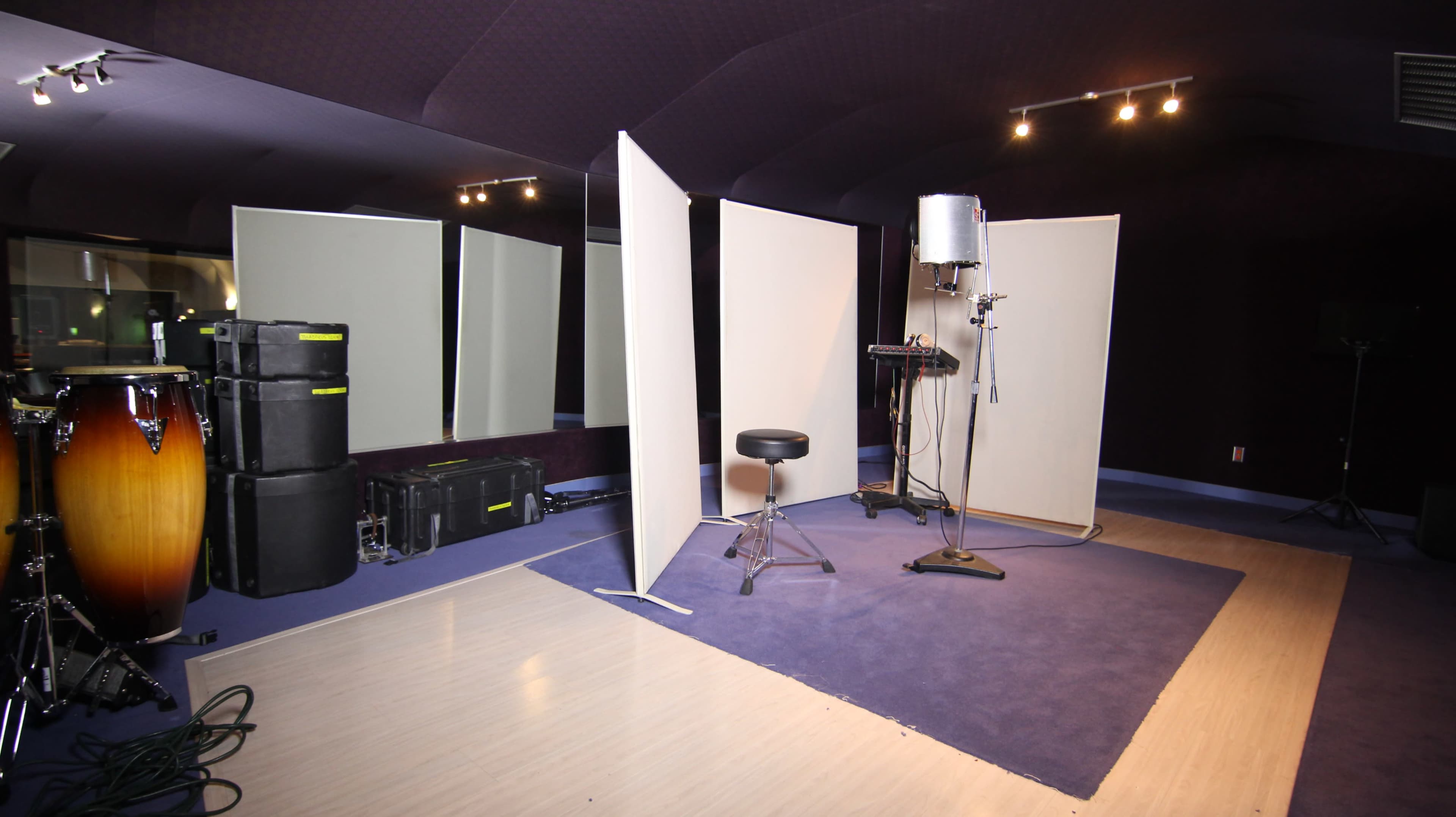 A soundproof recording studio with reflective panels, a microphone on a stand, a stool, and various music equipment.