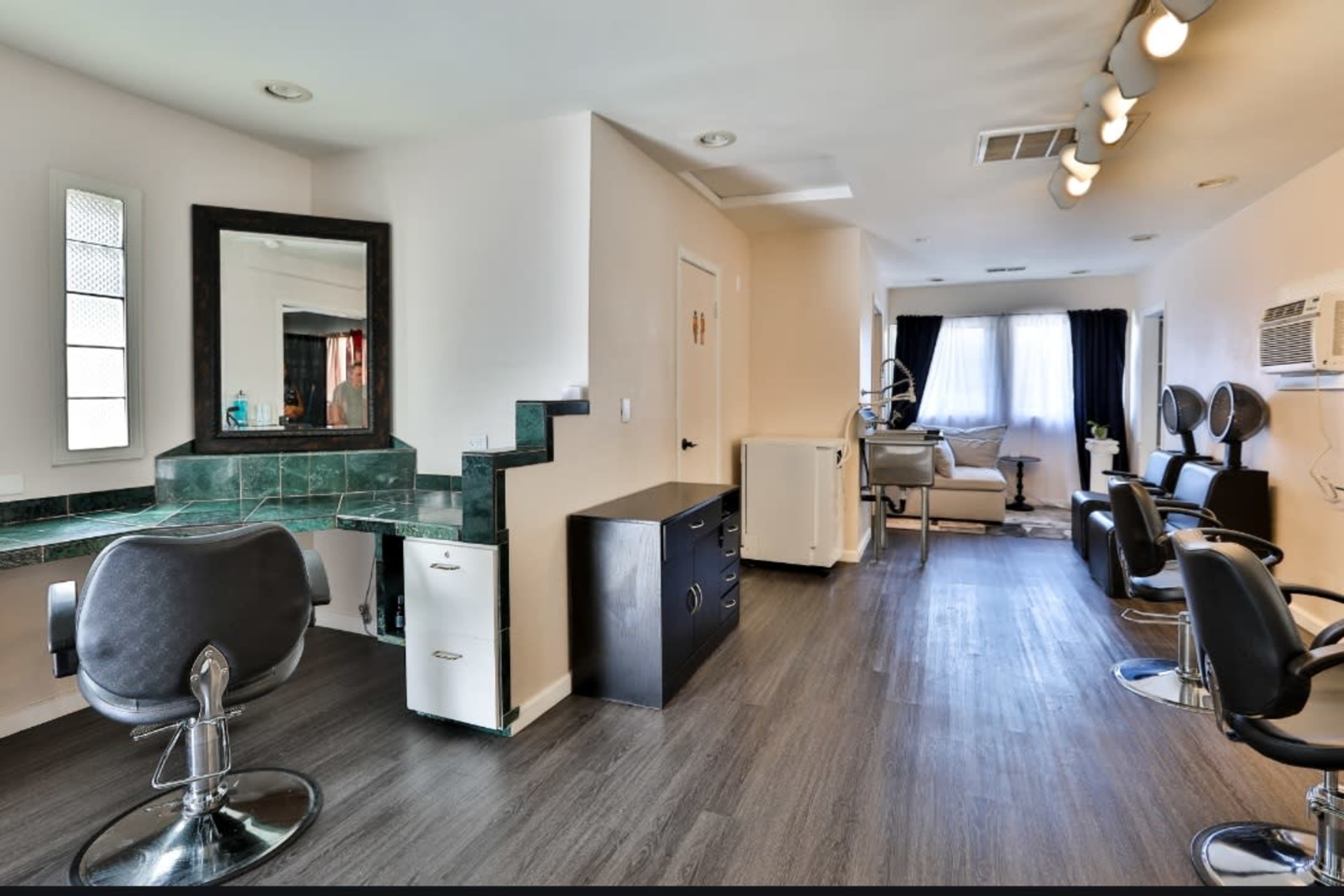 A modern hair salon interior with styling chairs, a mirror station, and a waiting area.