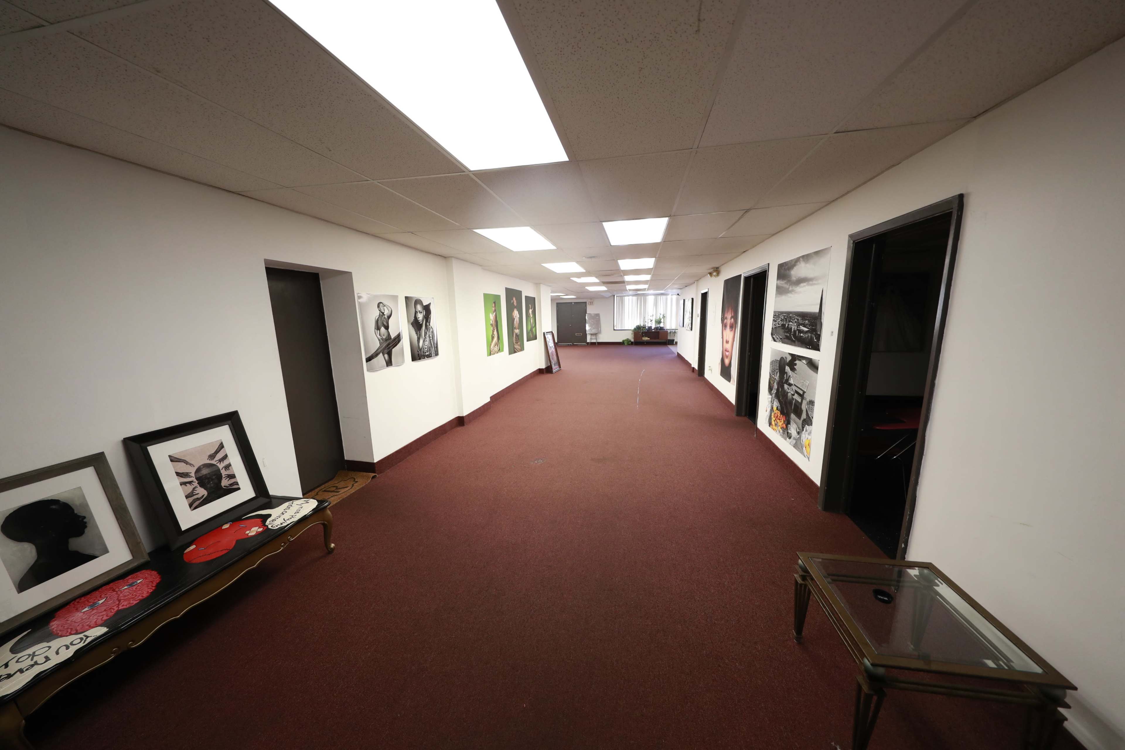 A long, narrow hallway with framed artwork and photographs displayed along one side.