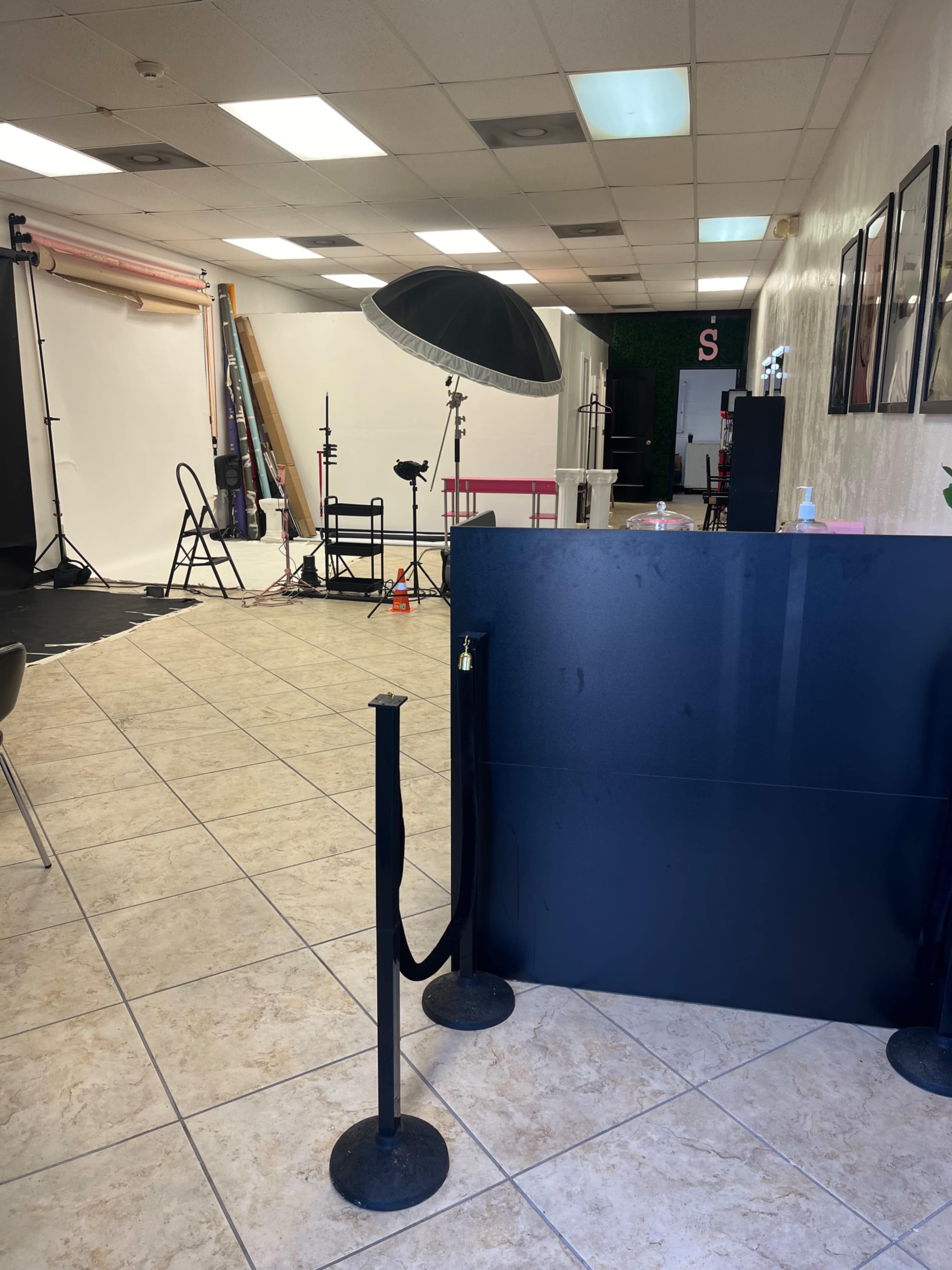 The image shows a photo studio interior with photography equipment, backdrops, and a reception area in view.