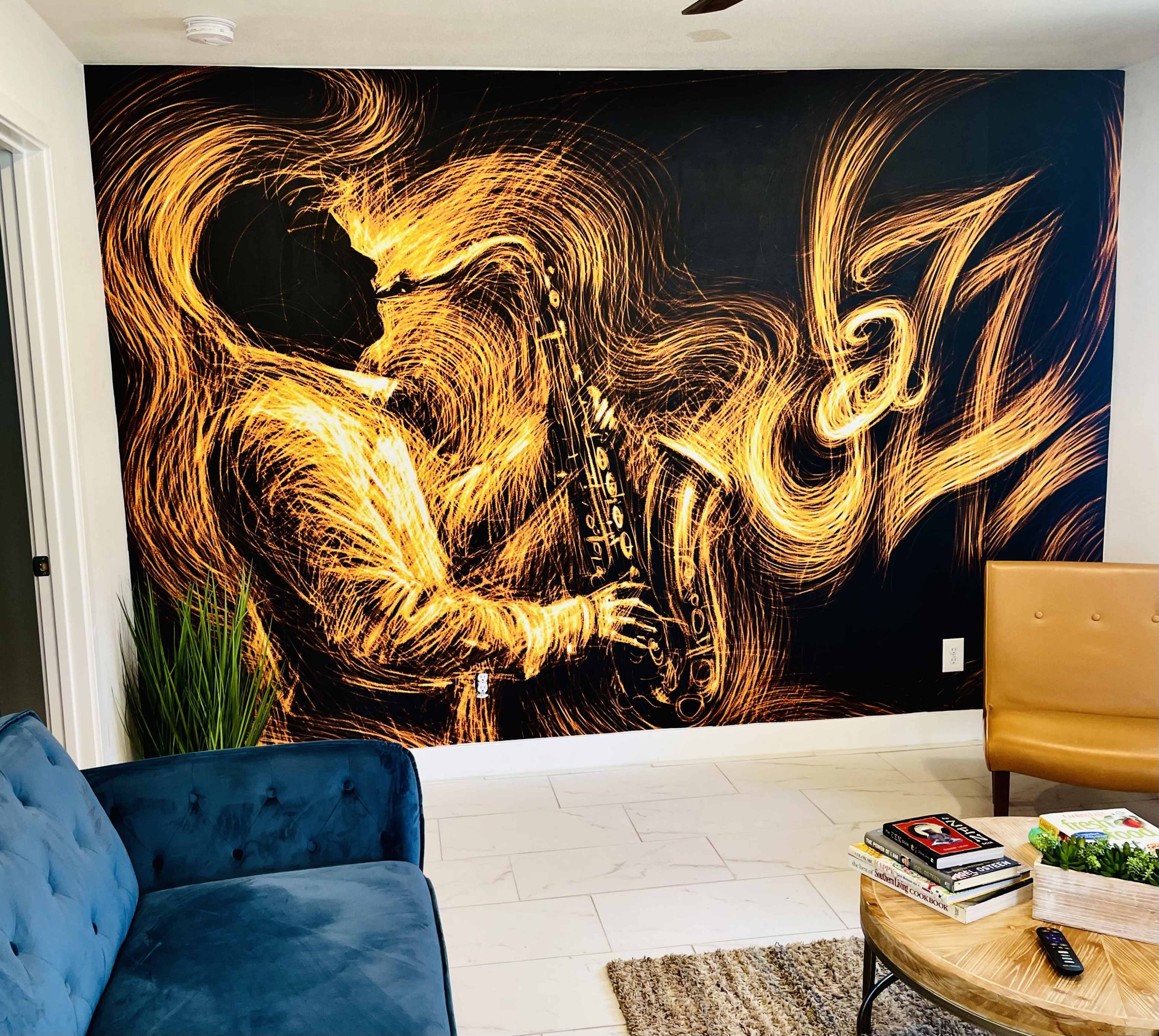 The image shows a living room with a wall mural of a saxophonist surrounded by swirling golden lines, alongside a blue couch and a brown armchair.