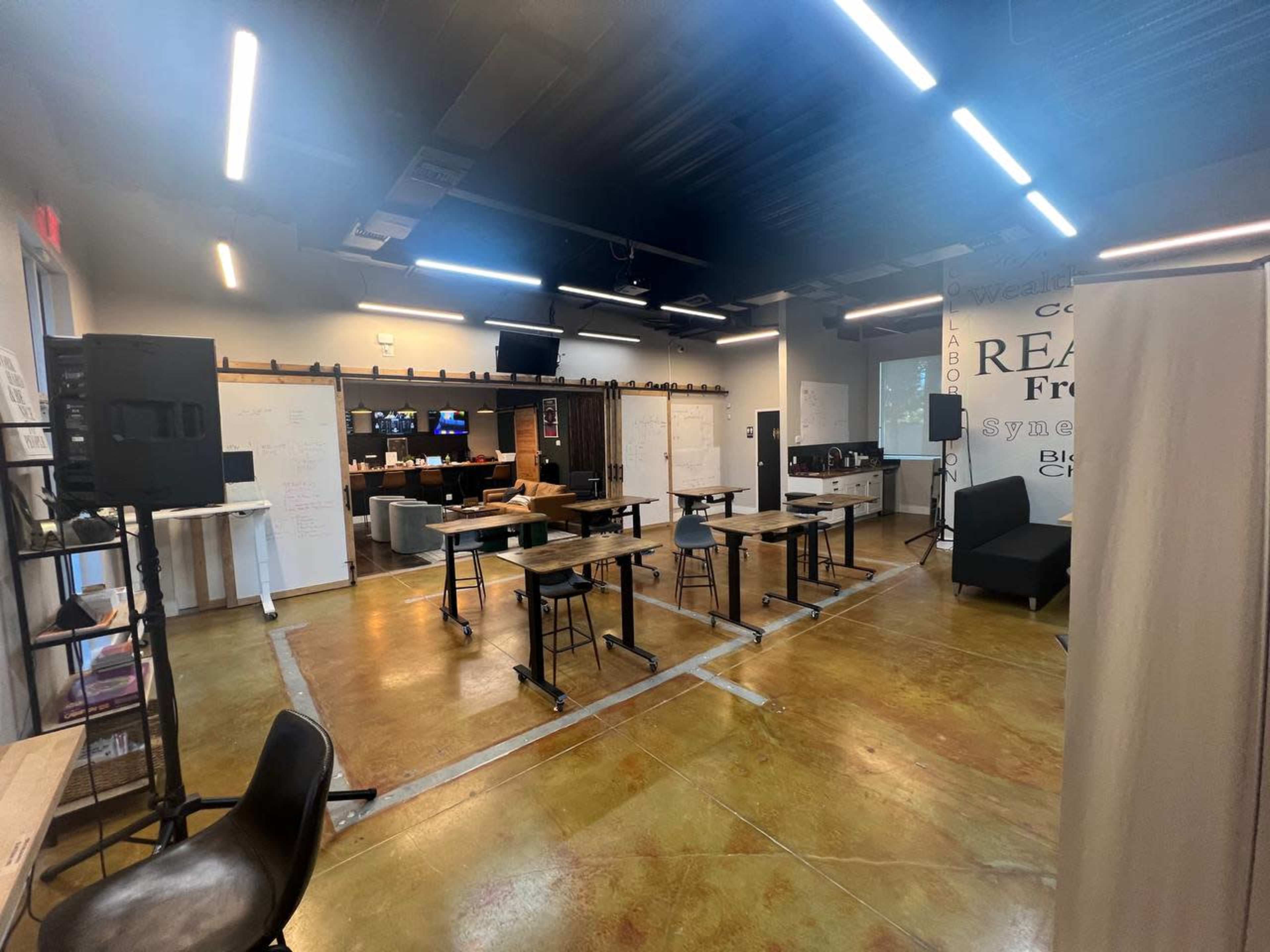 A modern classroom with rows of desks, audio equipment set up, and whiteboards on the walls.