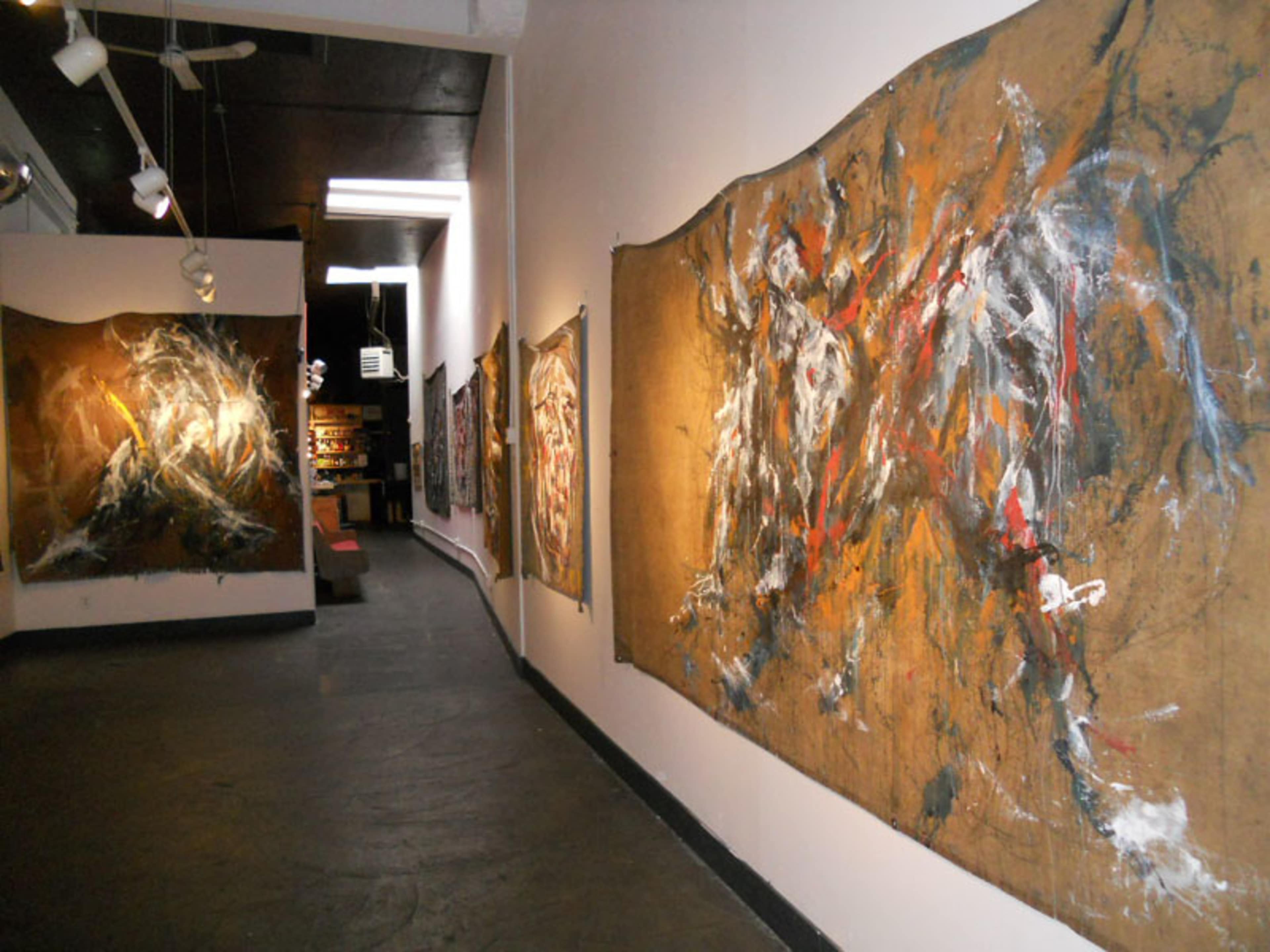 An art gallery with large, abstract paintings displayed on the walls along a corridor.