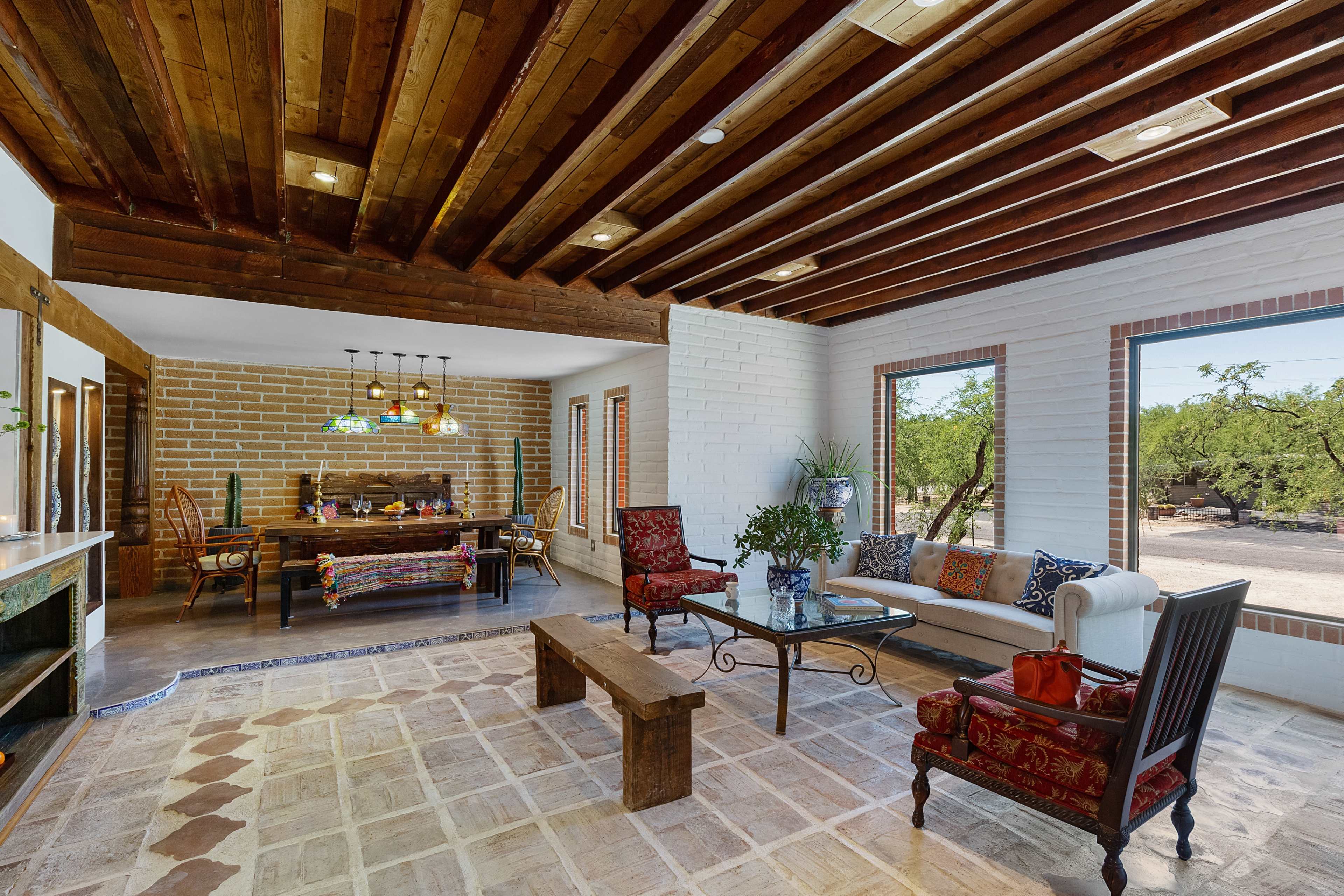 A spacious, modern interior with wooden beams, a rustic dining area, and large windows overlooking an outdoor landscape.