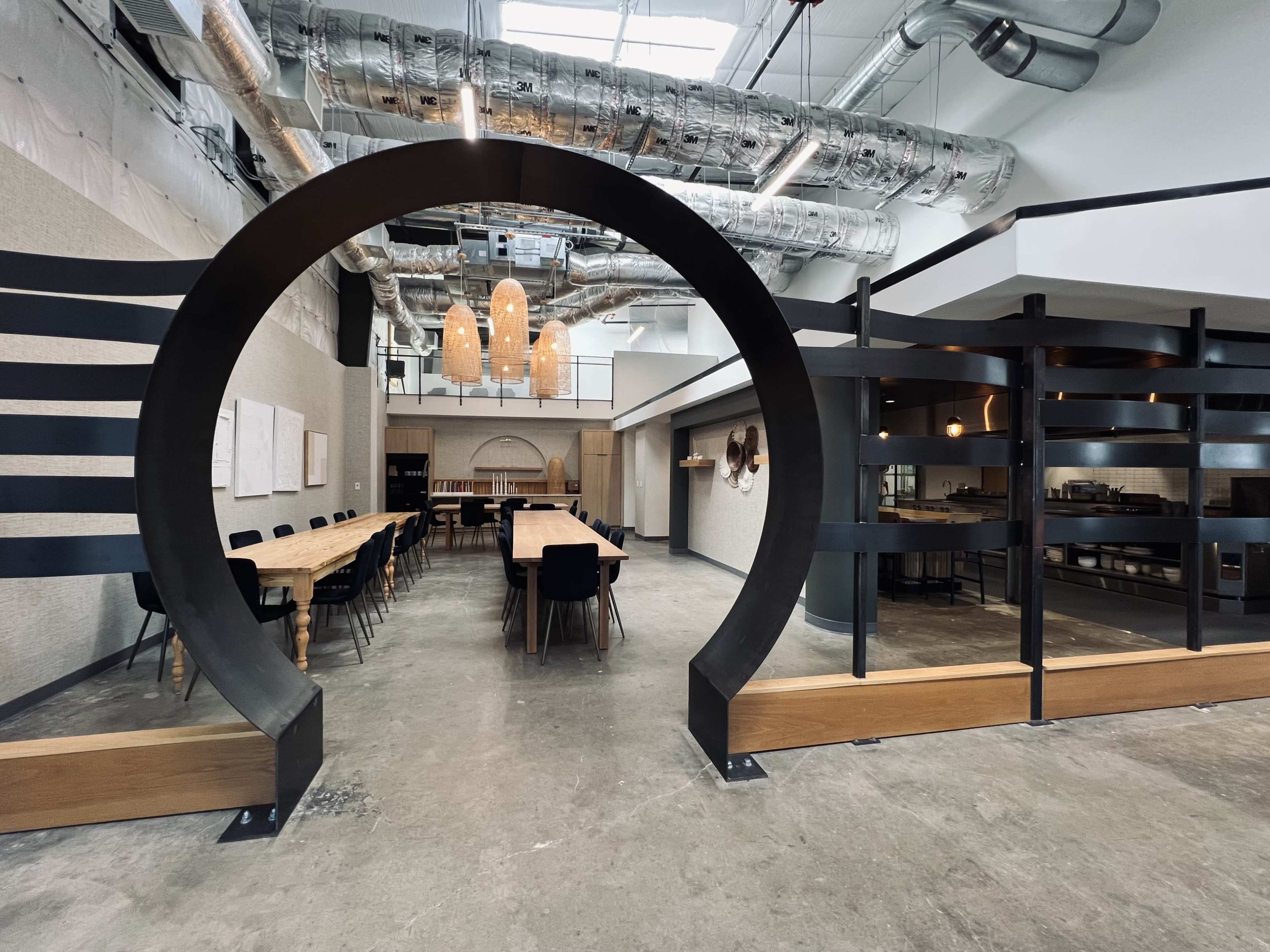 A modern interior of a restaurant featuring a large circular arch, a long communal table, and various seating arrangements.
