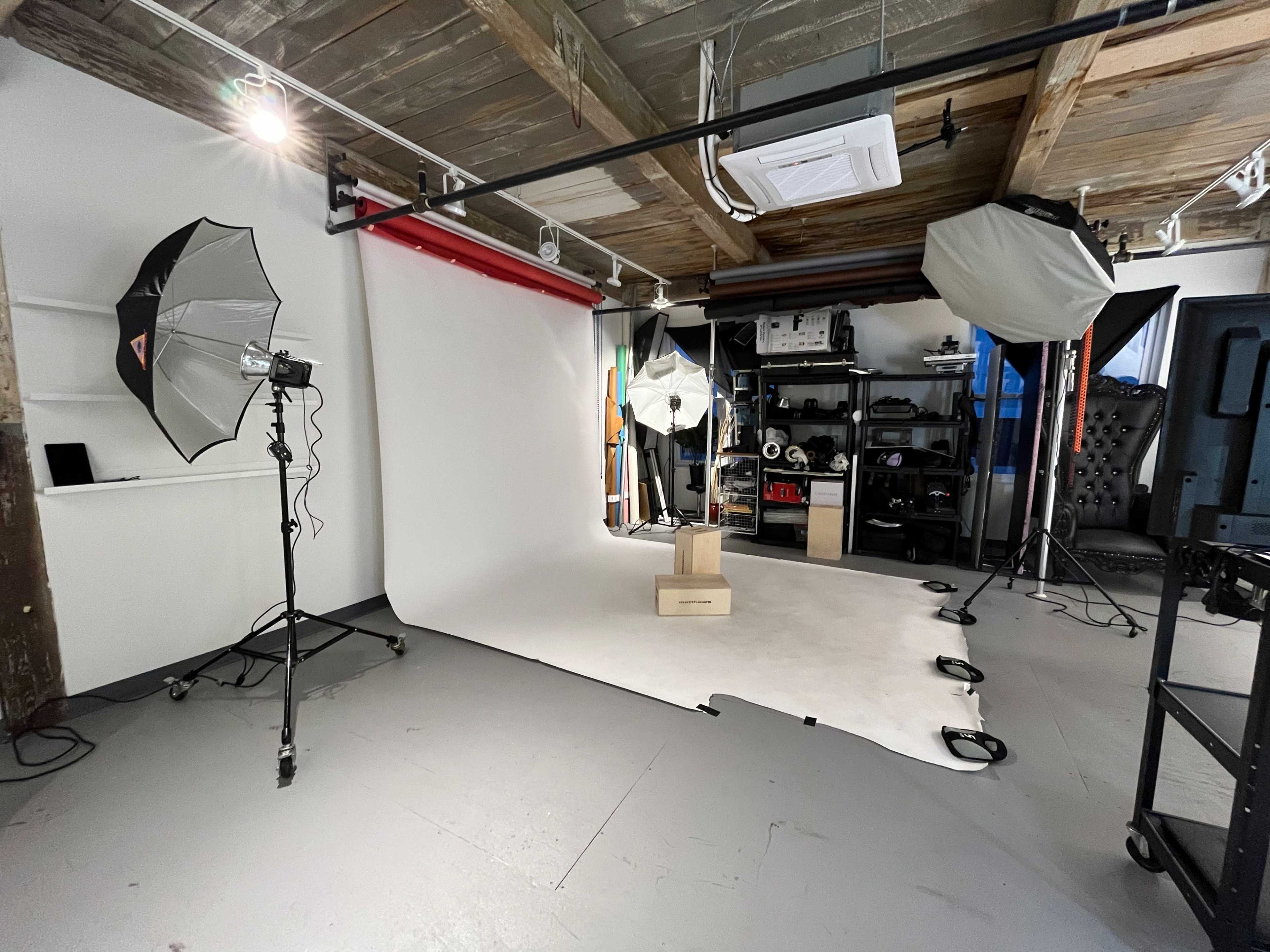 A photography studio with a backdrop, lighting equipment, and a shelf of gear.