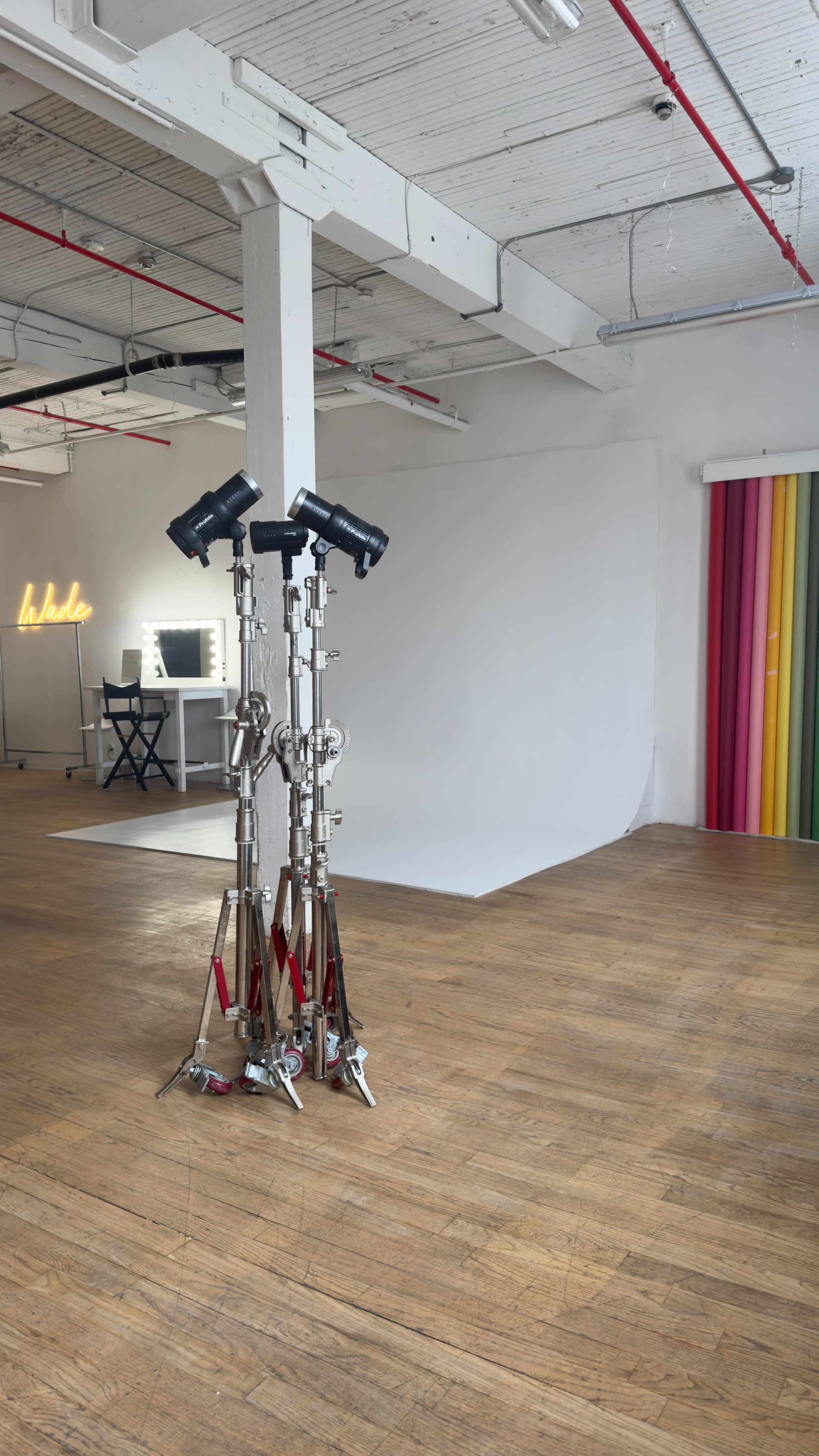 The image shows a photography studio with light stands, a backdrop, and colorful curtains in a spacious, well-lit room.