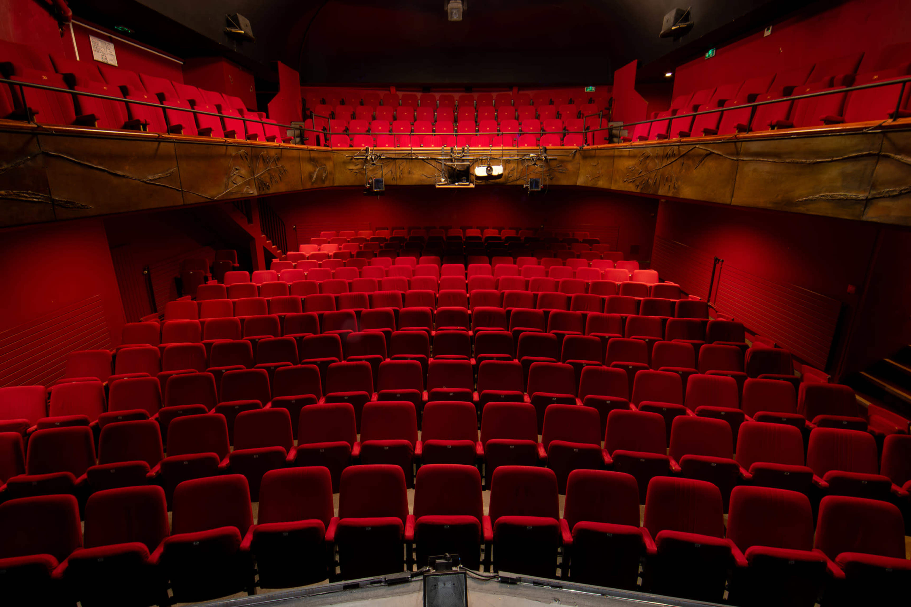 An empty theater with red seats arranged in a tiered layout.