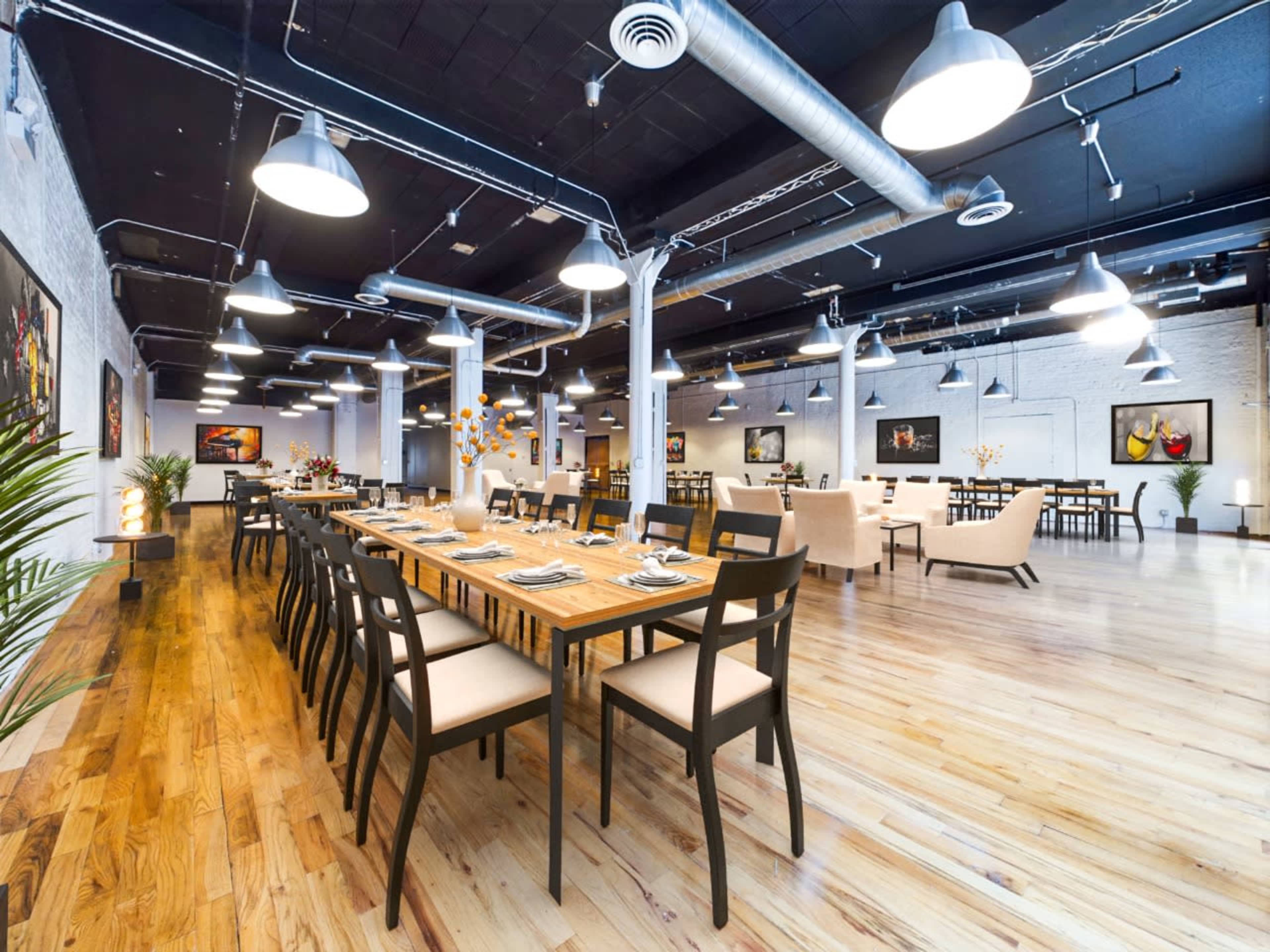 A spacious restaurant interior with wooden tables, black chairs, and artistic wall decor.