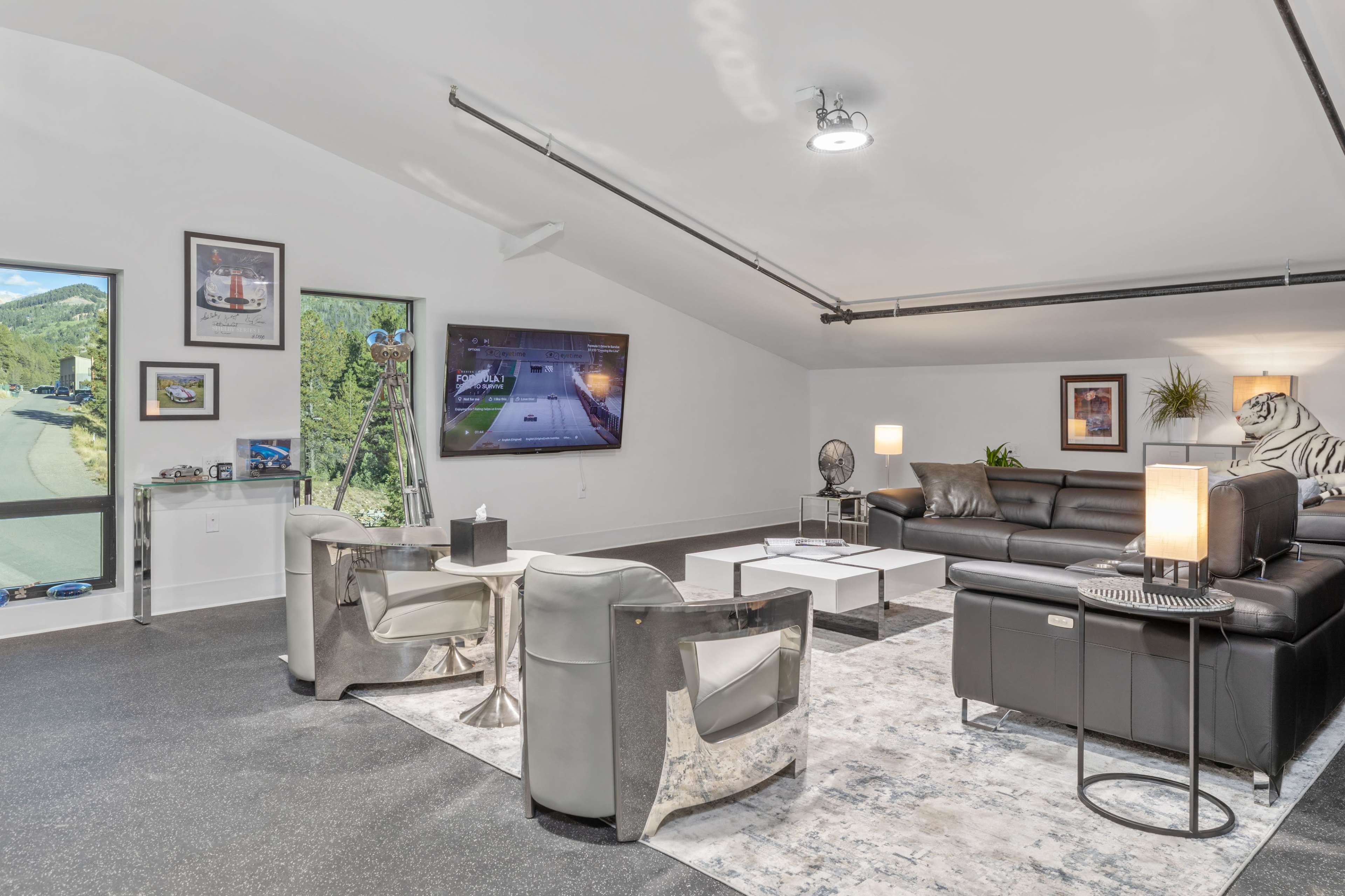 A modern lounge area features a large television, comfortable seating, and windows that overlook a scenic outdoor view.