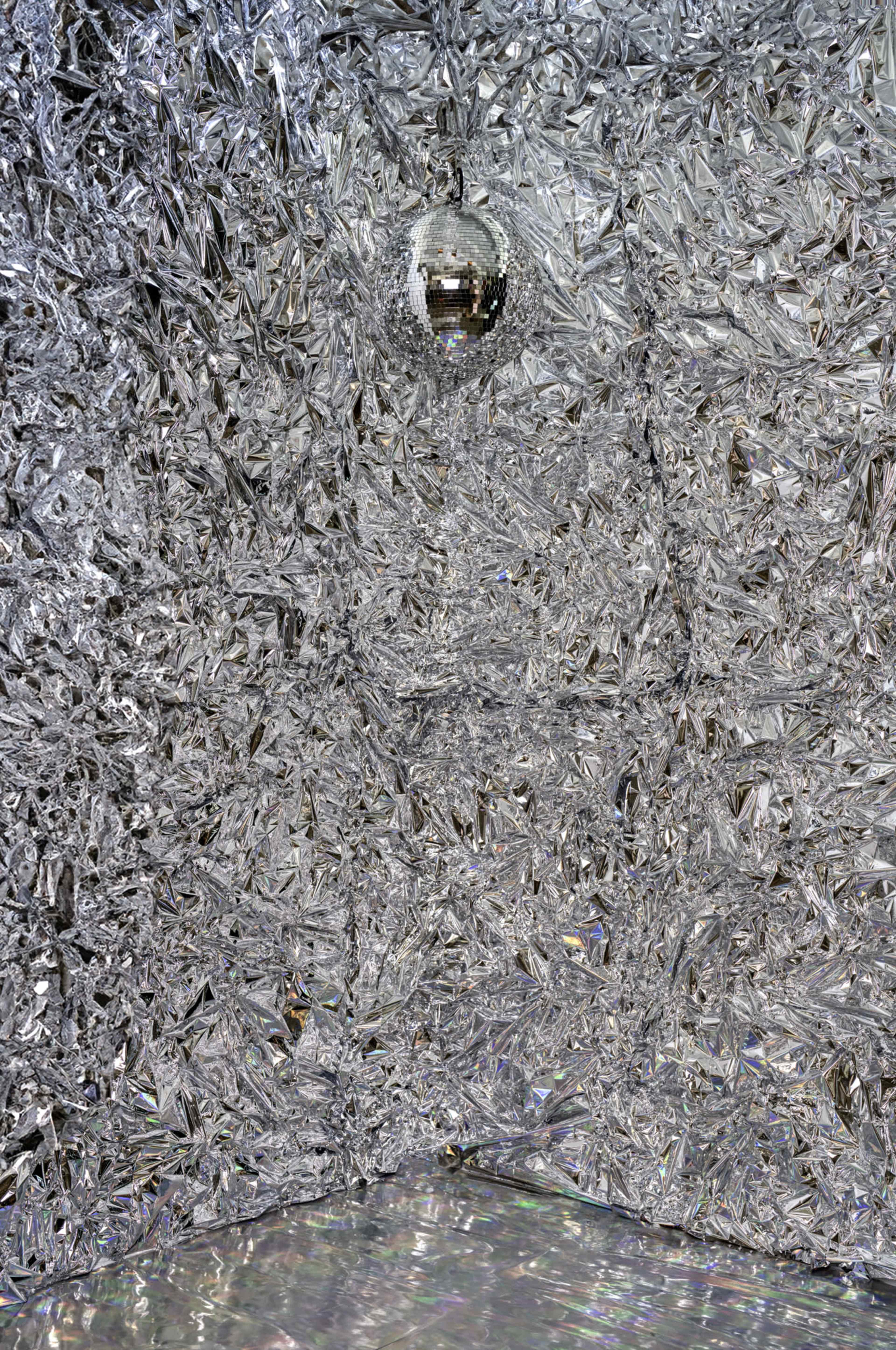 A room covered in reflective, silver, crystal-like surfaces with a disco ball hanging from the ceiling.