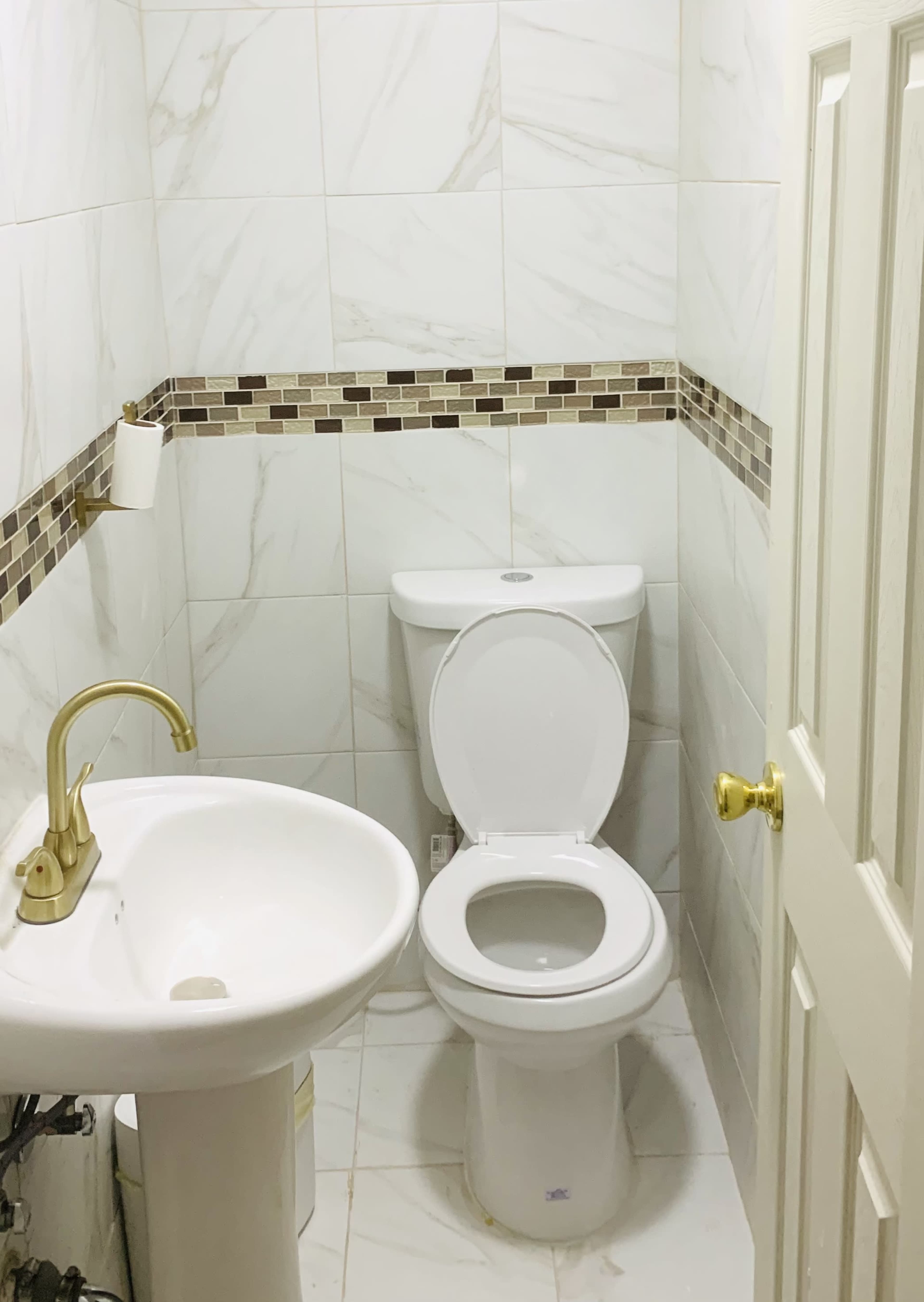 A small bathroom with a toilet, a sink, and tiled walls.